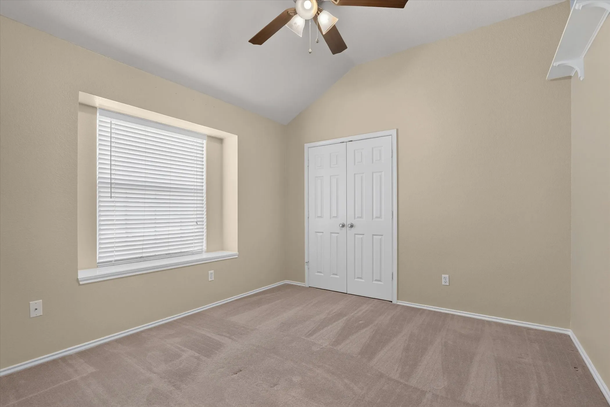 Vaulted ceiling with a ceiling fan, carpeted flooring, window with blinds, and bi-fold closet doors