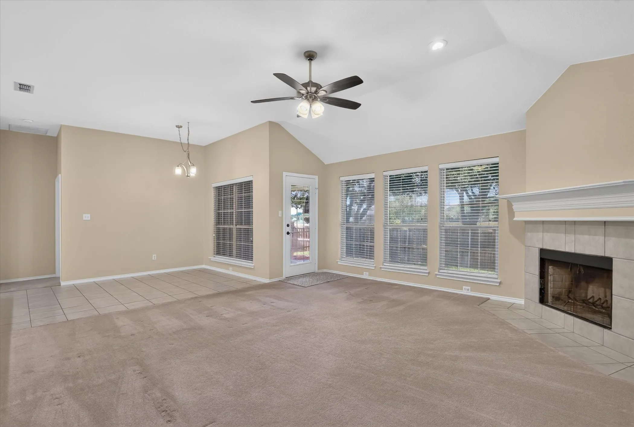 Vaulted ceilings, a ceiling fan, and a tiled fireplace with a mantel