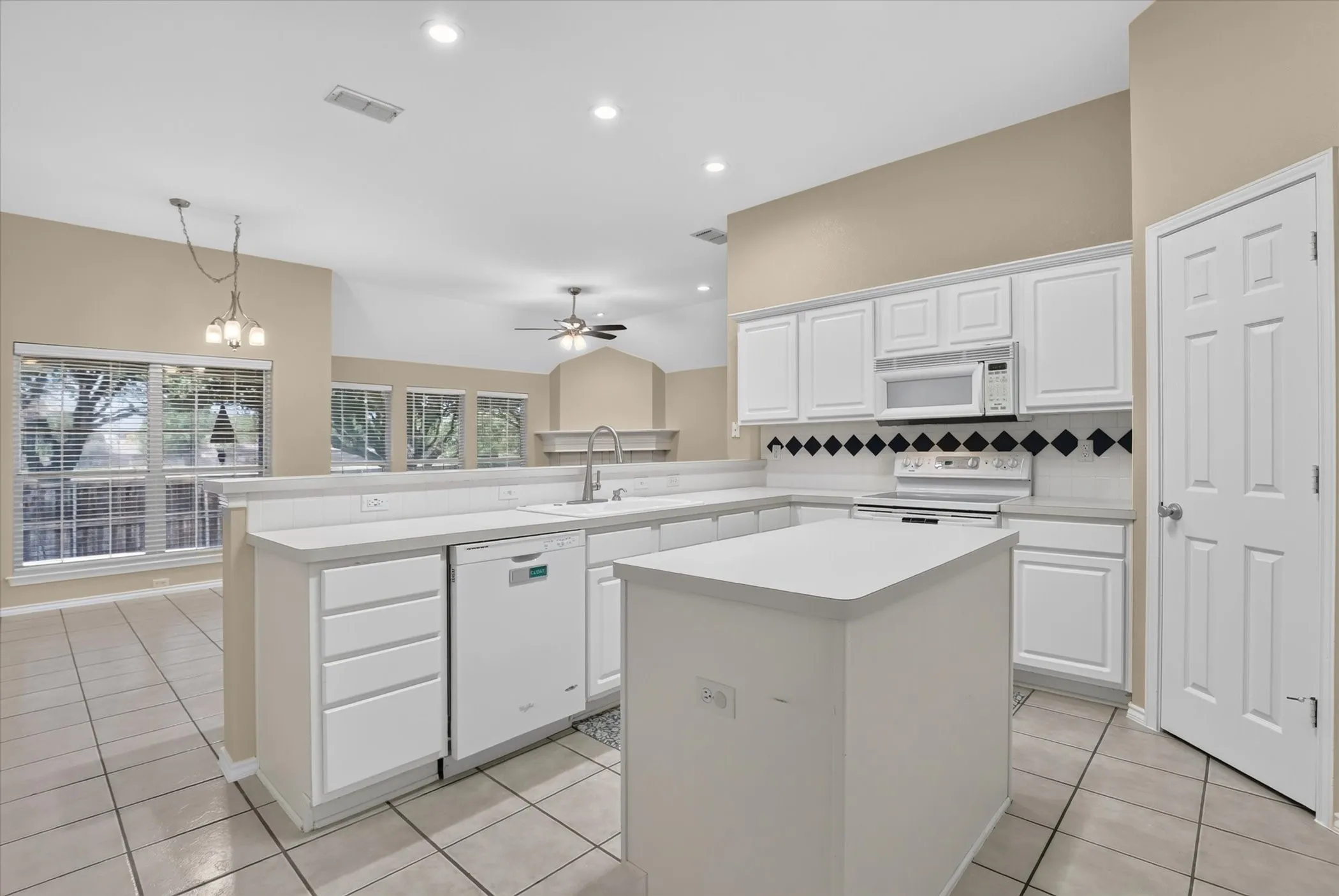Kitchen featuring an island, white cabinetry, tile flooring, and a dishwasher