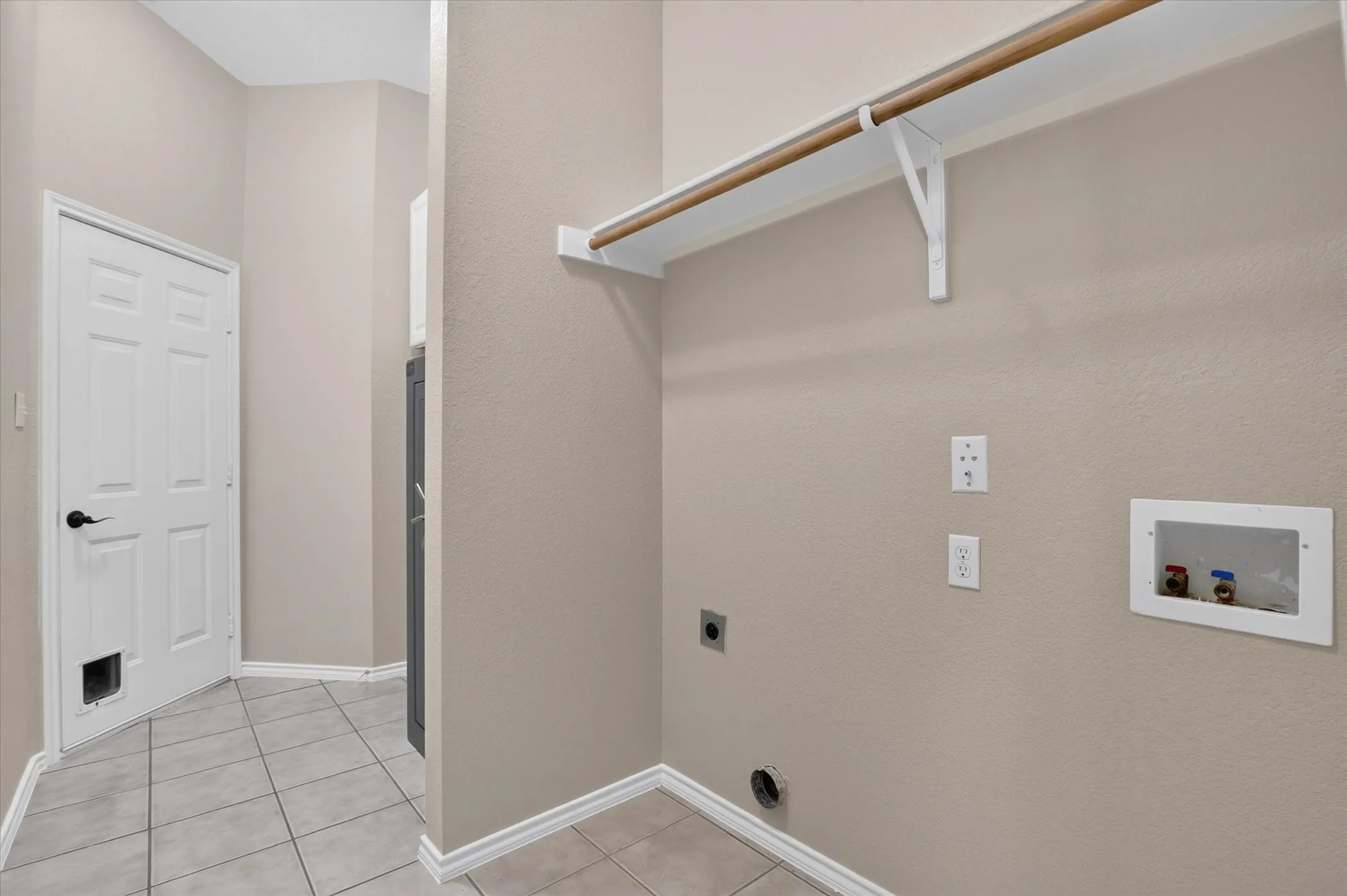 Utility area featuring tile flooring, a mounted clothes rod, and white baseboards