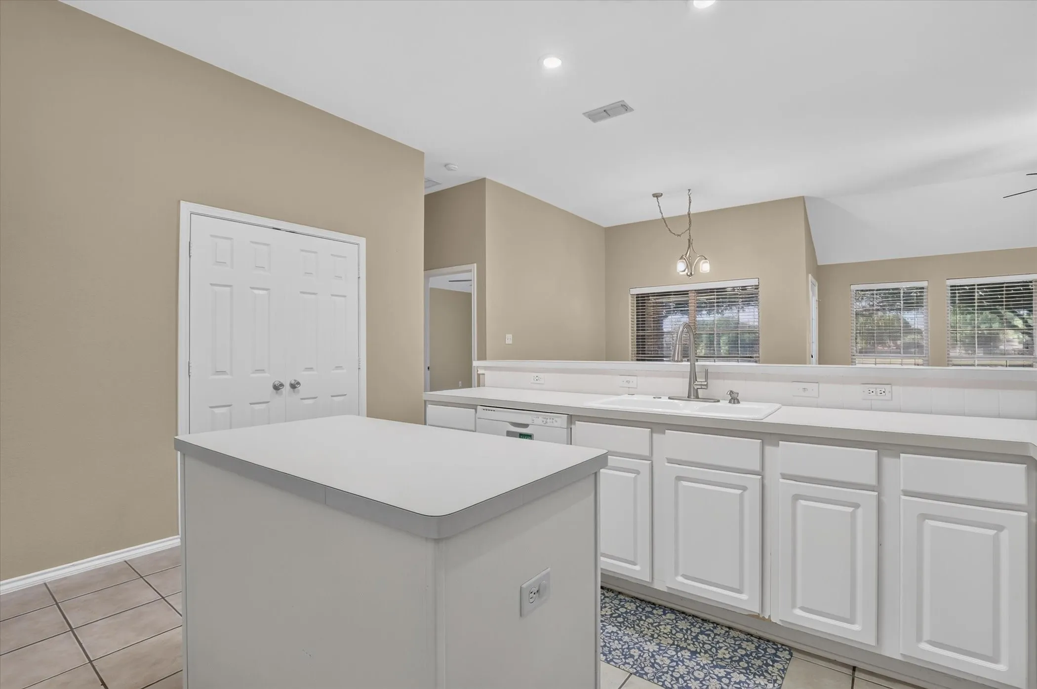 Kitchen featuring an island, white cabinetry, integrated sink, and recessed lighting