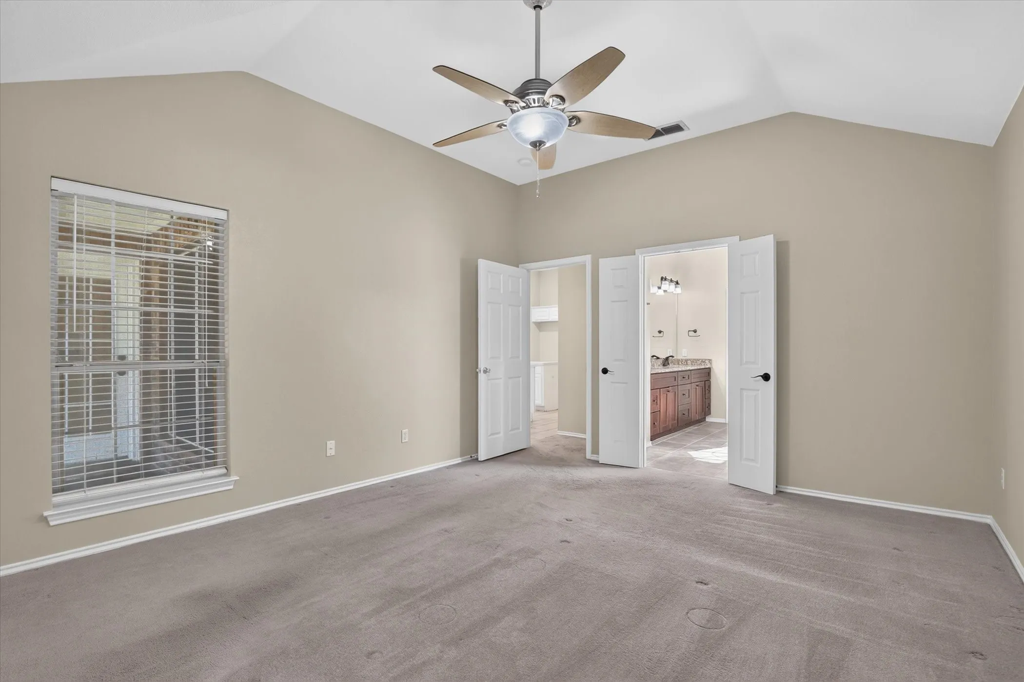 Vaulted ceiling with a ceiling fan, neutral wall paint, and carpeted flooring