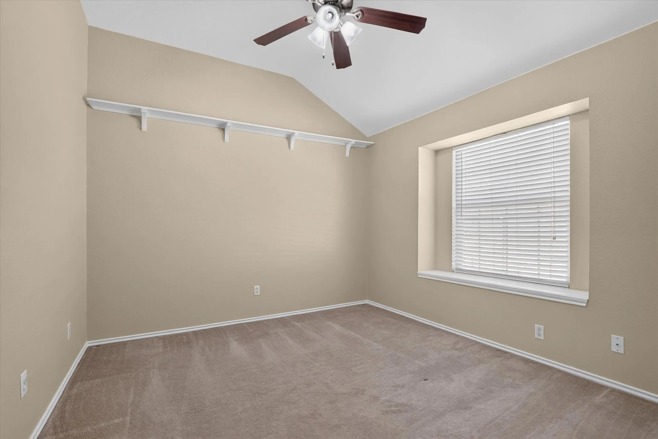 Vaulted ceiling, ceiling fan, recessed window, window blinds, and built-in shelving