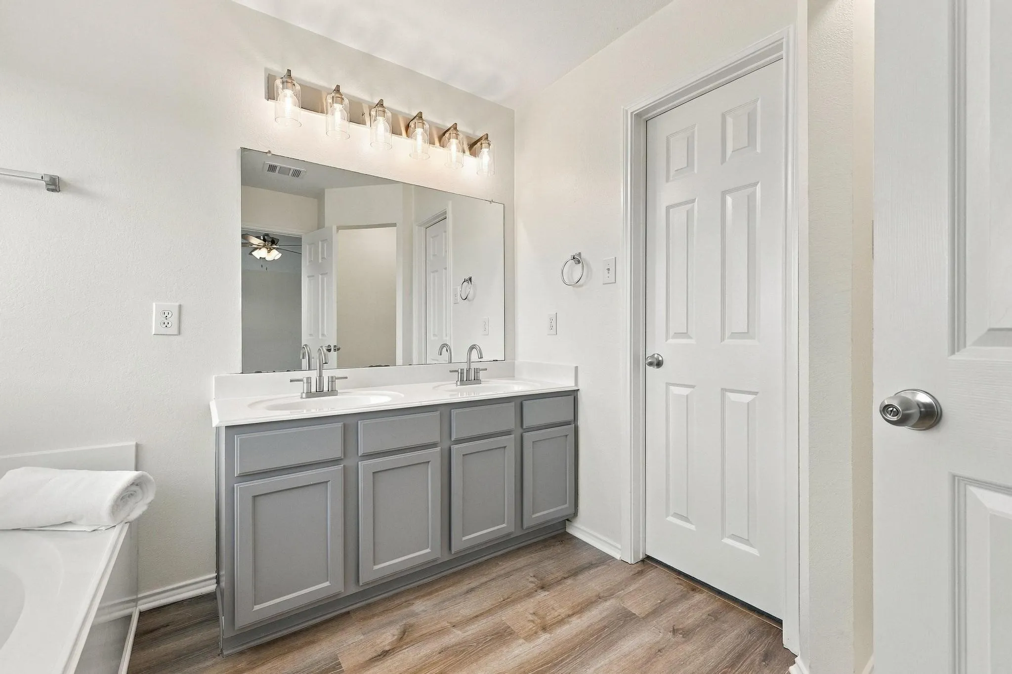 Dual vanity with gray cabinetry, white countertops, dual undermount sinks, and wood-finish flooring