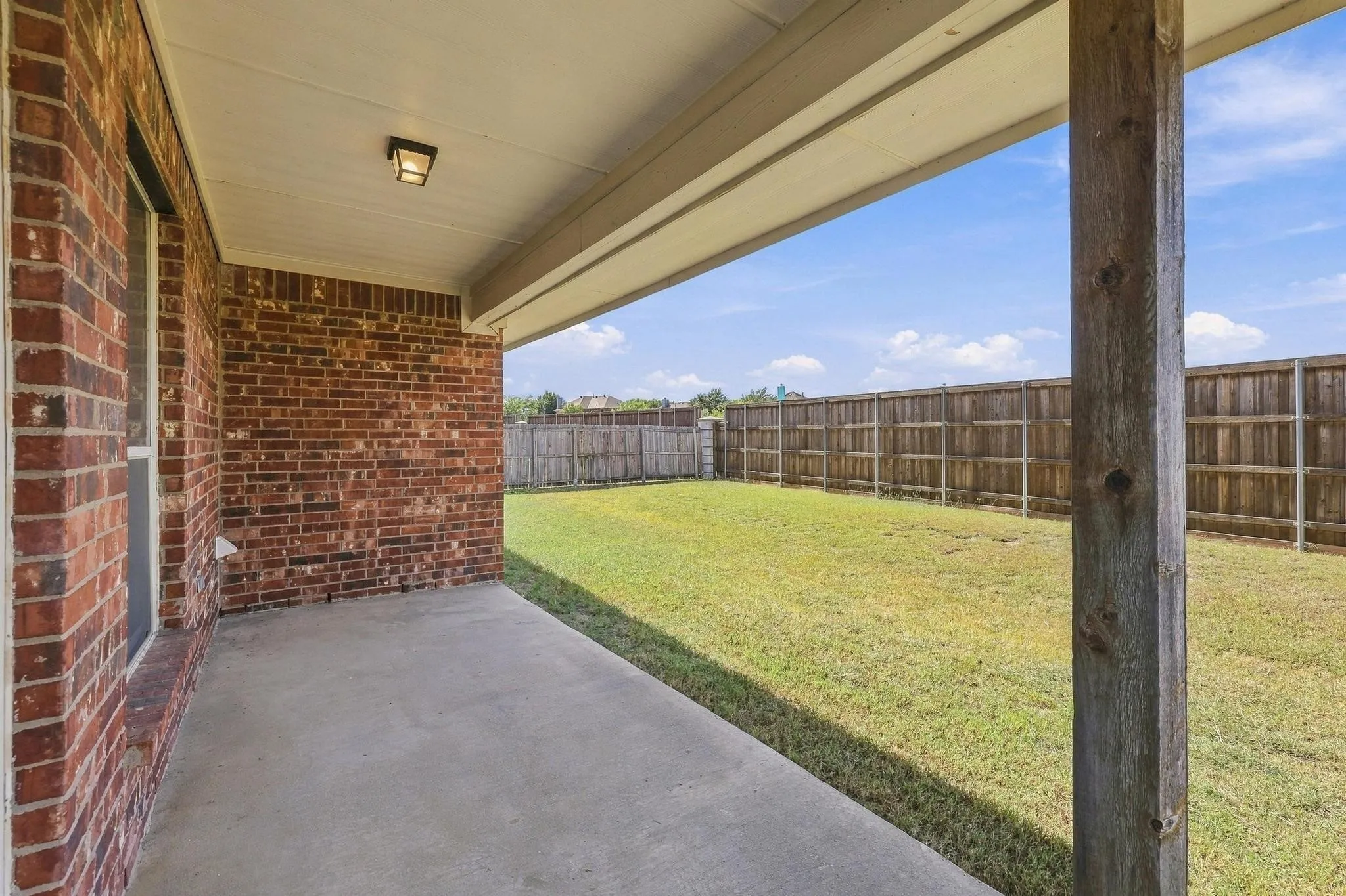 Covered patio with a concrete slab and brick exterior