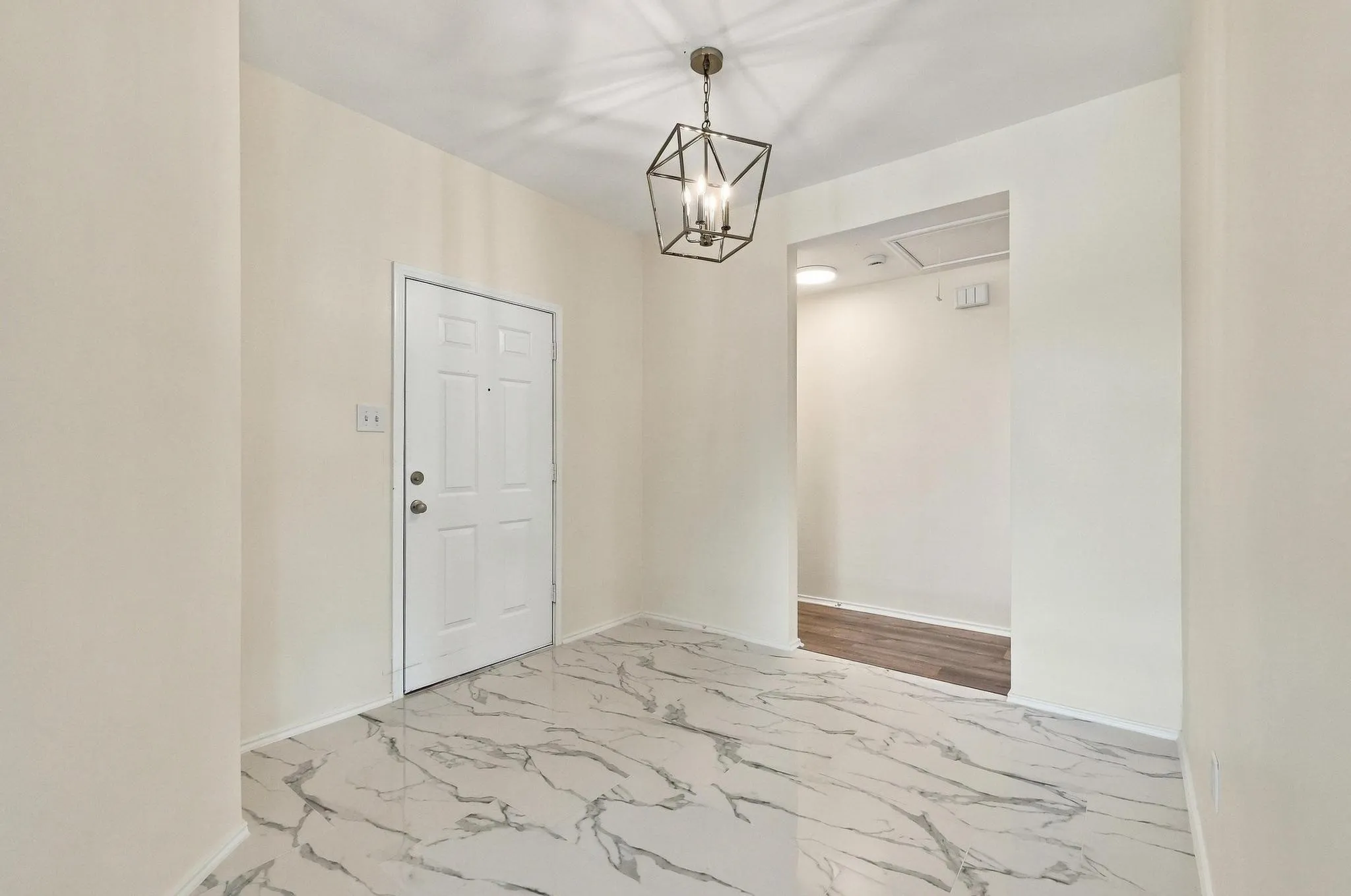 Entryway featuring marbled floor tiles, a decorative geometric chandelier, and a paneled entry door