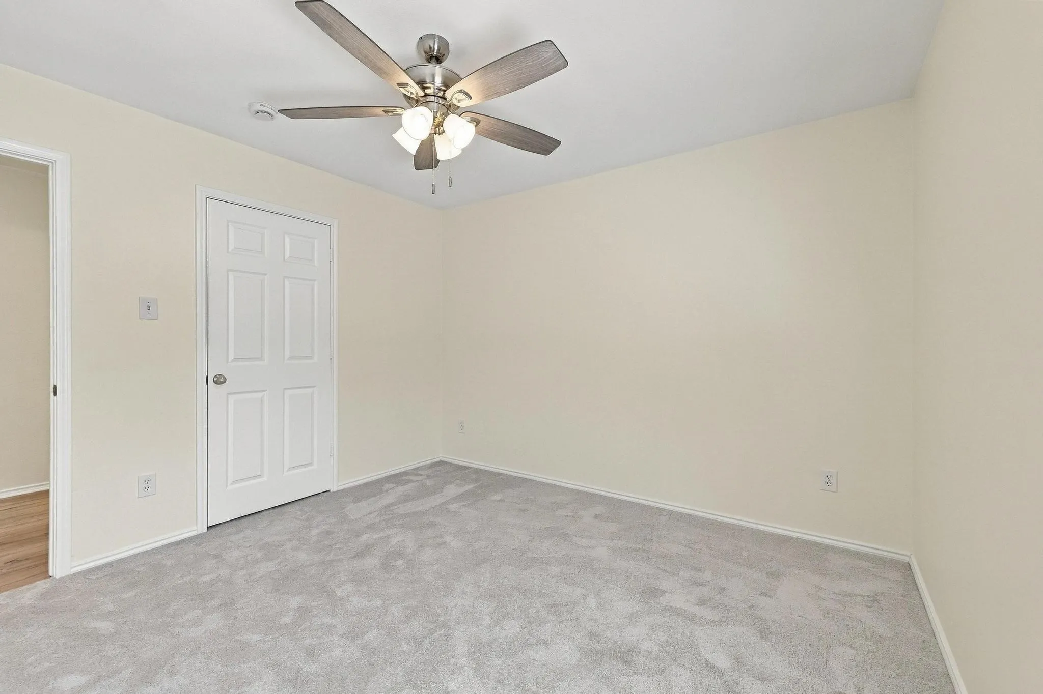 Neutral wall color, ceiling fan with light fixture, light gray carpeting, paneled interior door, and white trim