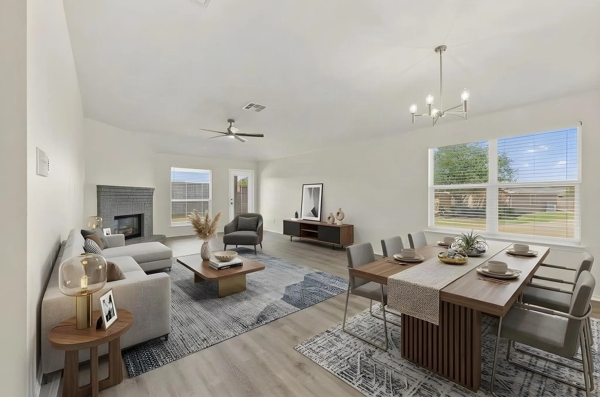 This room has been virtually staged using AI to illustrate its potential-concept living and dining area featuring wood-finish flooring, a fireplace with a stone surround, a contemporary ceiling fan, and a modern chandelier