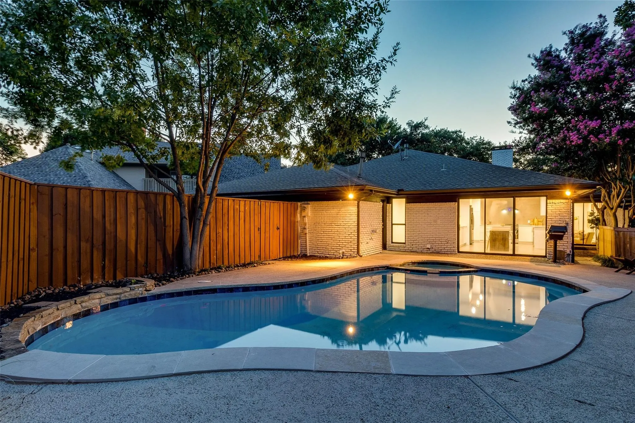 Pool at dusk featuring a patio area and an in ground hot tub