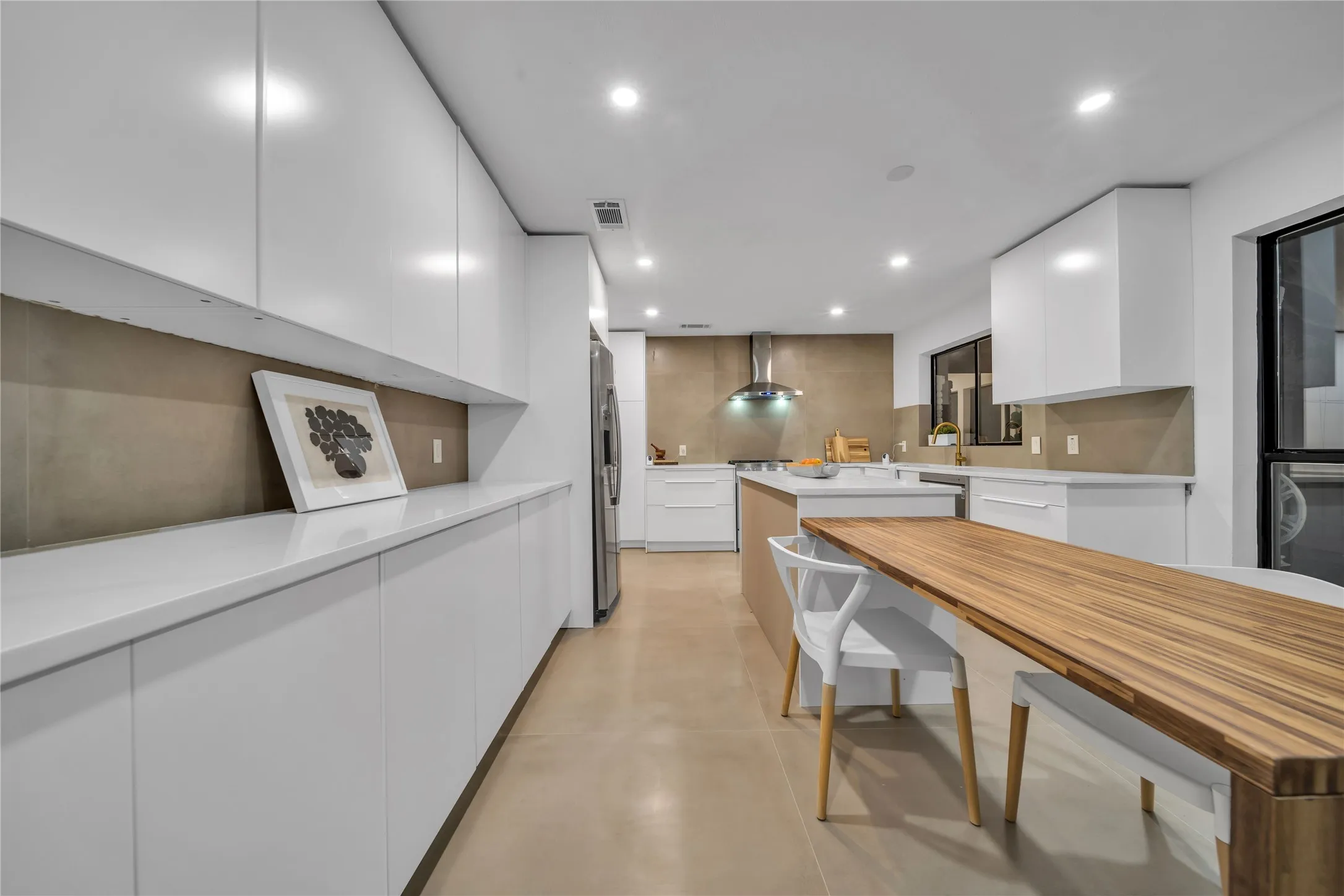 Kitchen with white cabinets, wall chimney exhaust hood, appliances with stainless steel finishes, and tasteful backsplash