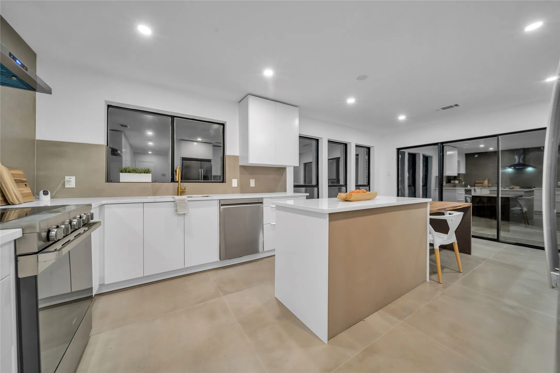 Kitchen with a center island, wall chimney exhaust hood, stainless steel appliances, sink, and white cabinets