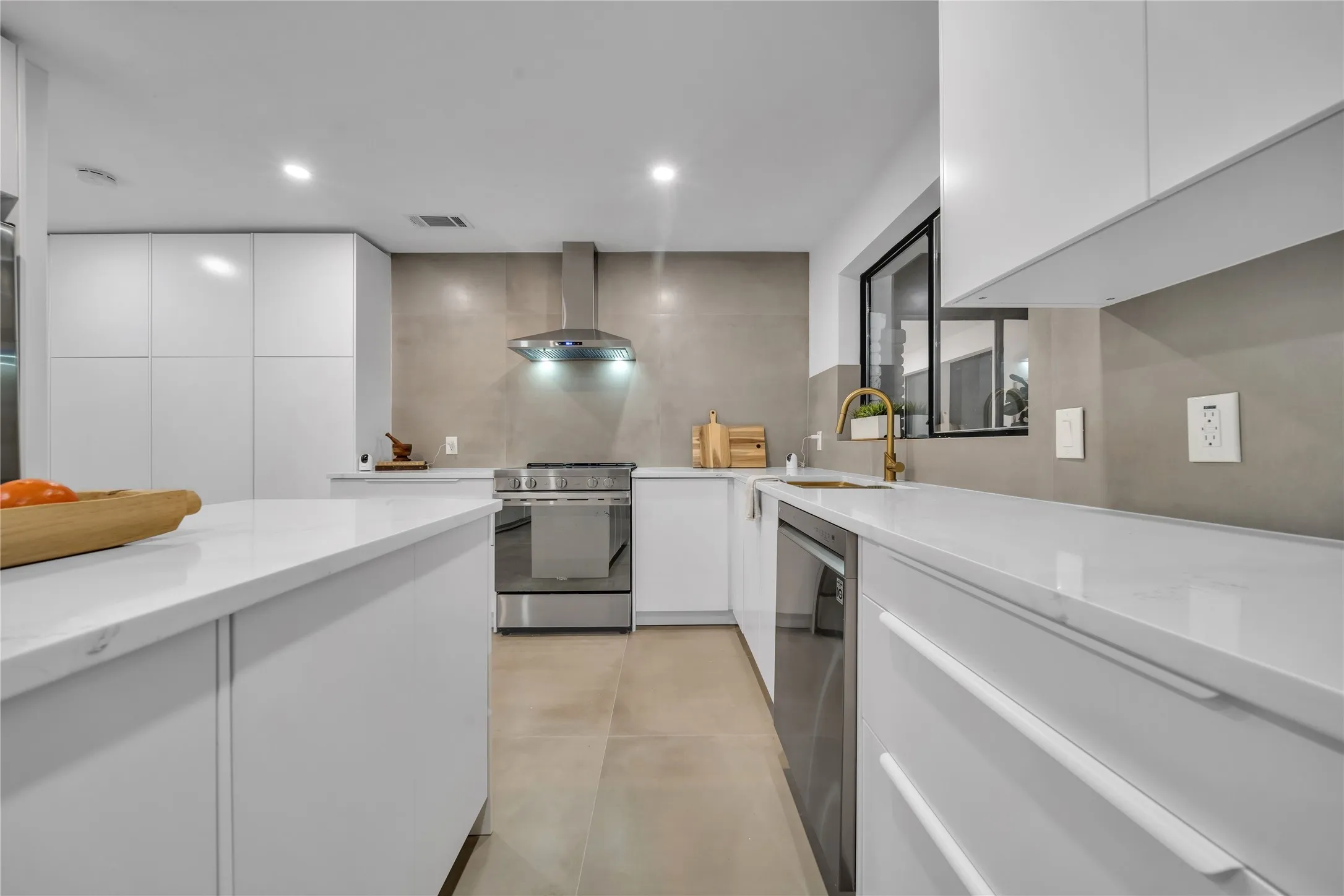 Kitchen featuring white cabinets, appliances with stainless steel finishes, wall chimney exhaust hood, and sink