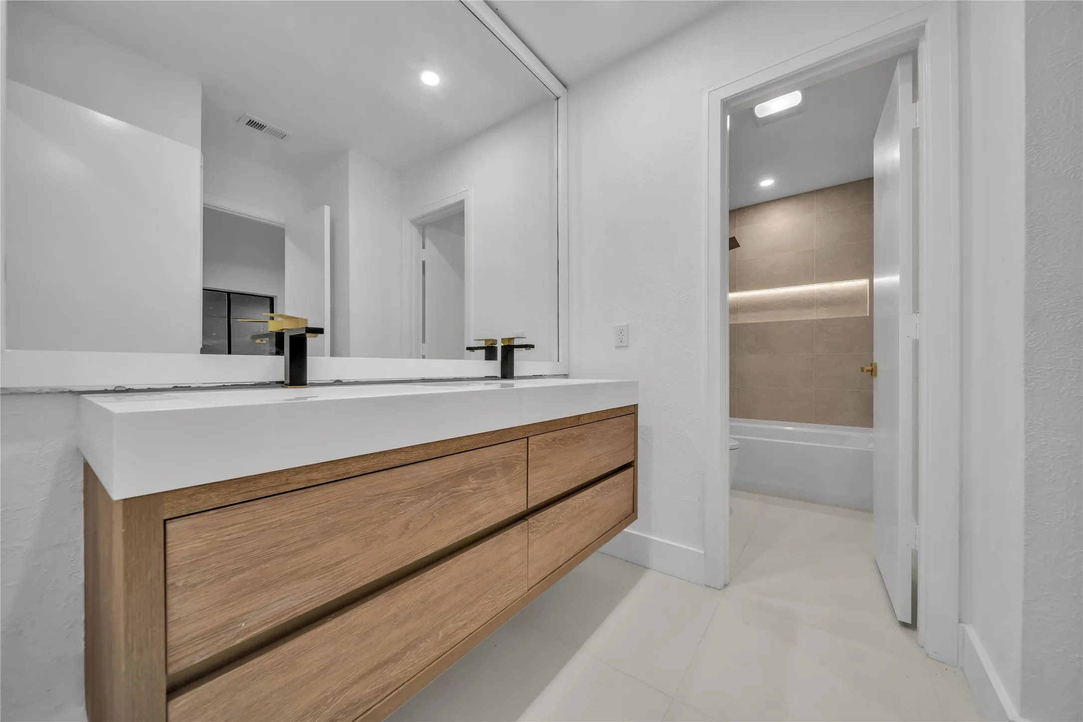 Full bathroom featuring toilet, vanity, tile patterned floors, and tiled shower / bath