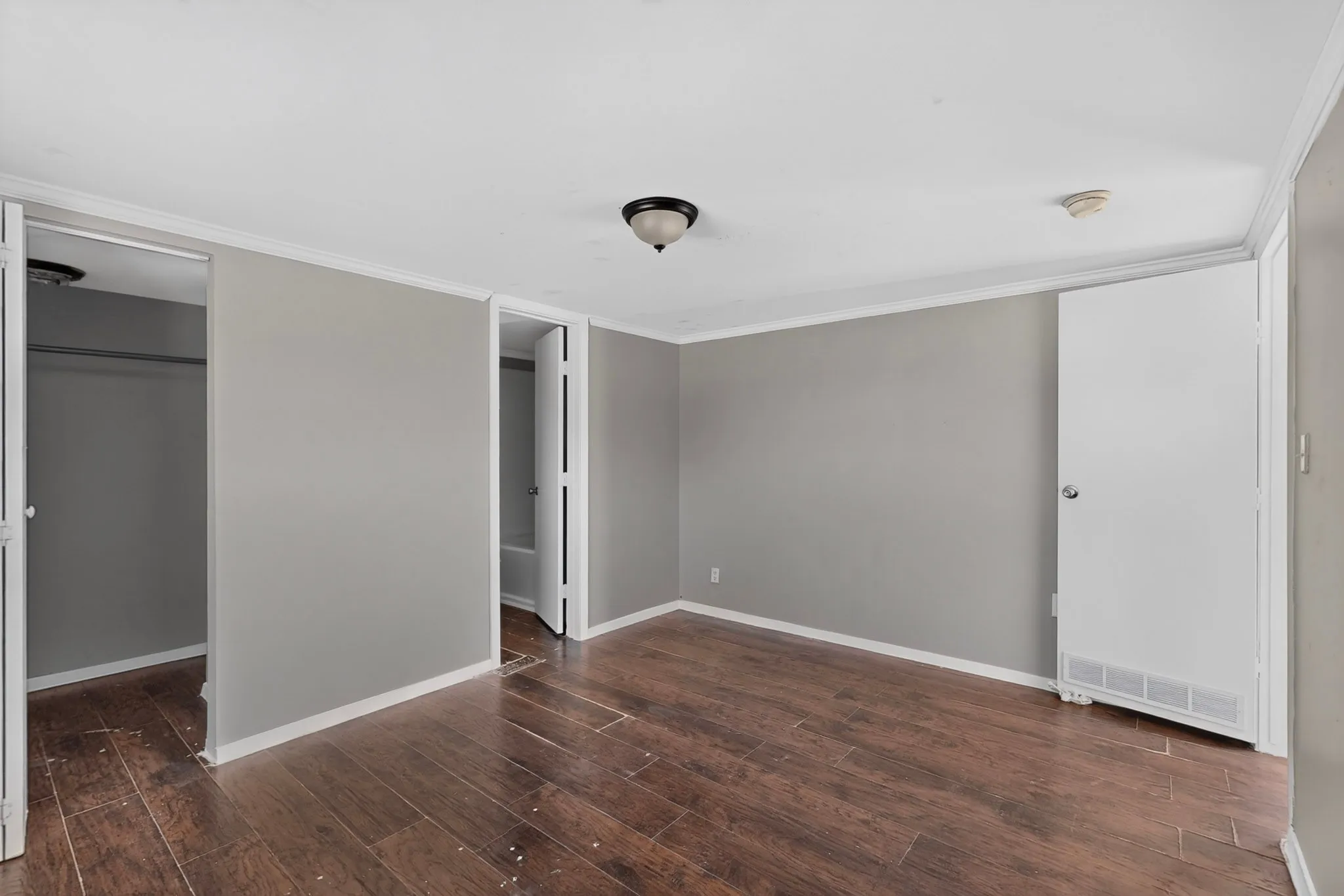 Wood-finish flooring, light gray wall paint, white trim, and ceiling-mounted light fixture