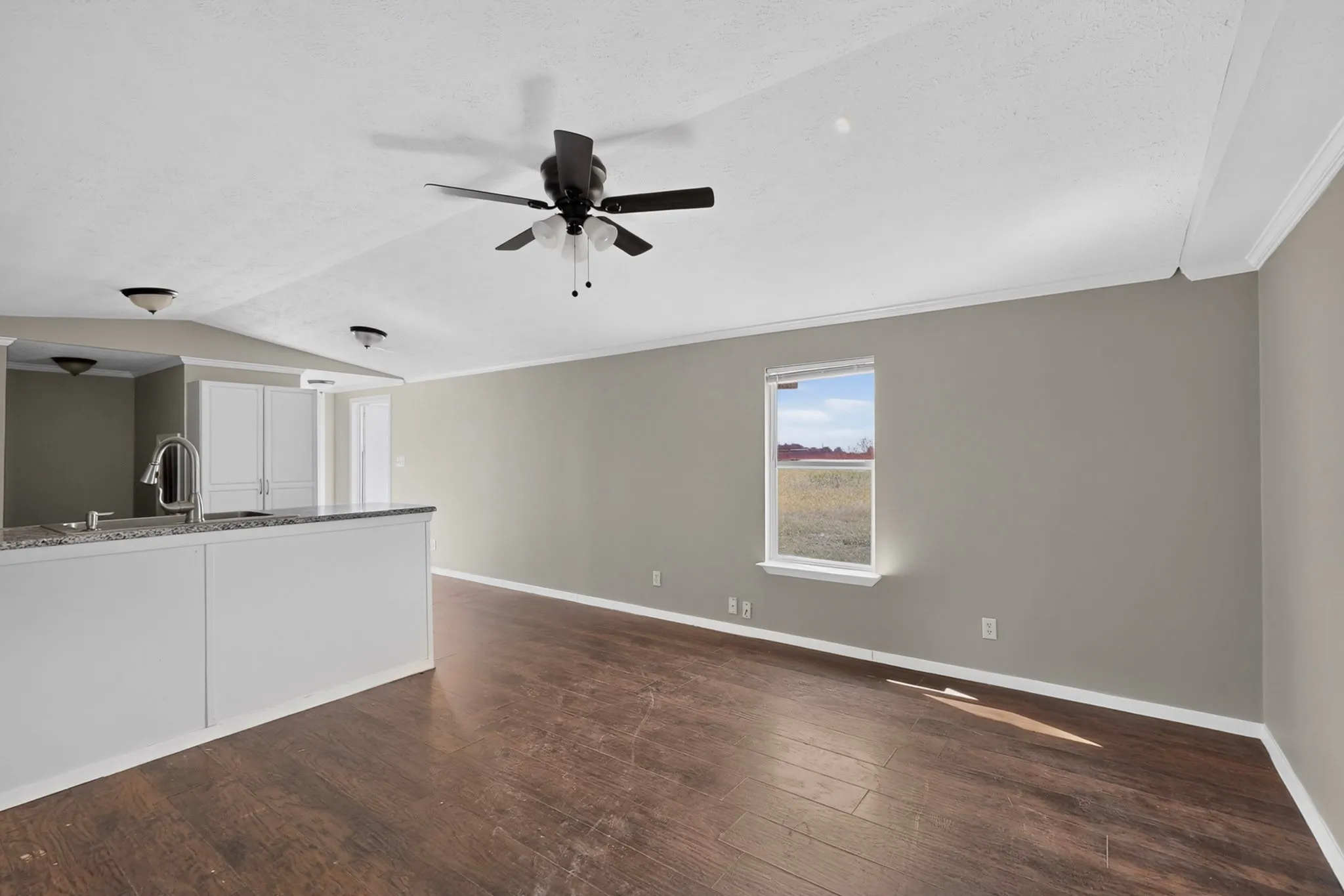 Open-concept living space featuring wood-finish flooring, a contemporary ceiling fan, and crown molding