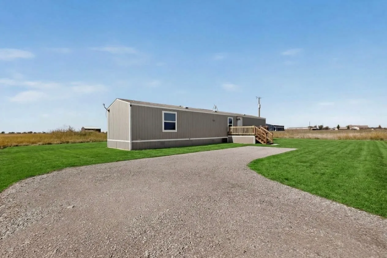 Gravel driveway leading to residence with light gray siding