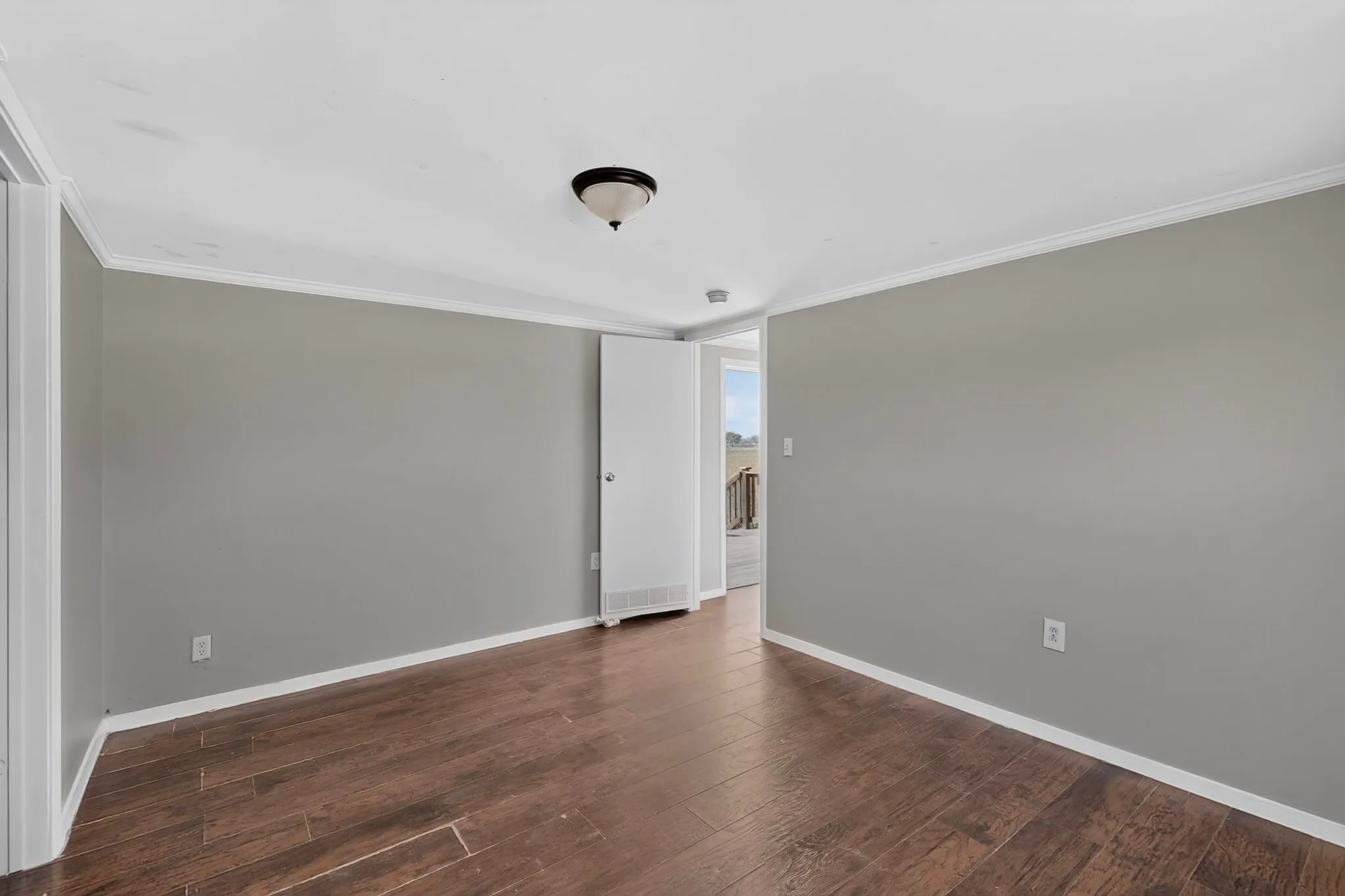 Wood-finish flooring, light gray walls, white trim, and a semi-flush mount ceiling light