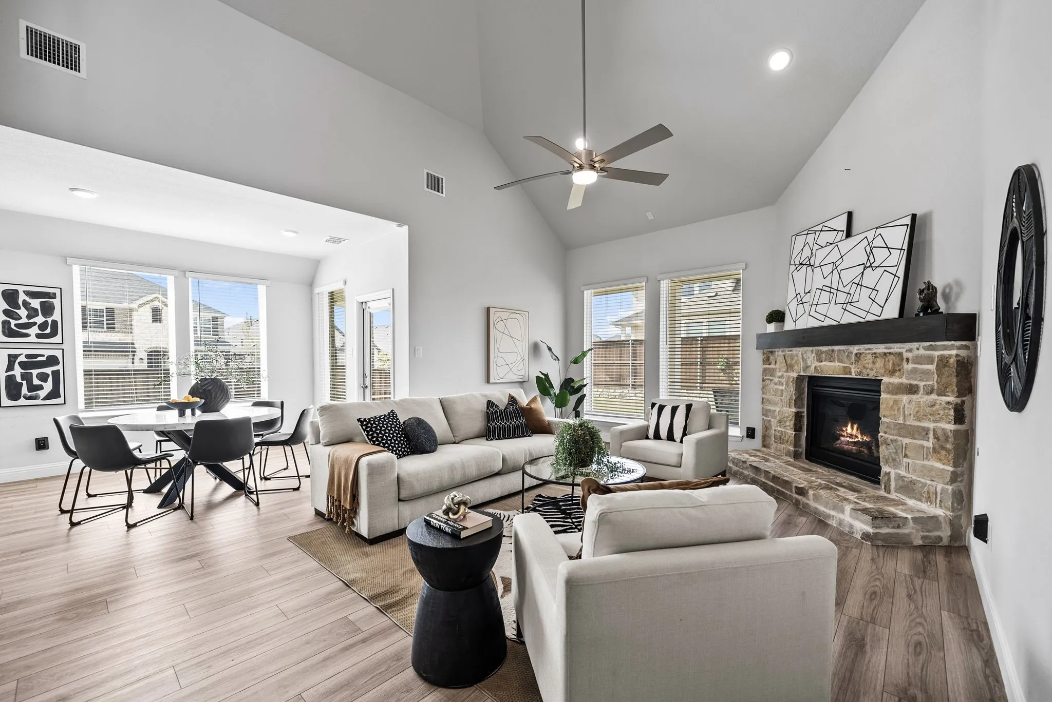 Vaulted ceilings, a stone-faced fireplace with a substantial wood mantel, and multiple large windows define this living space