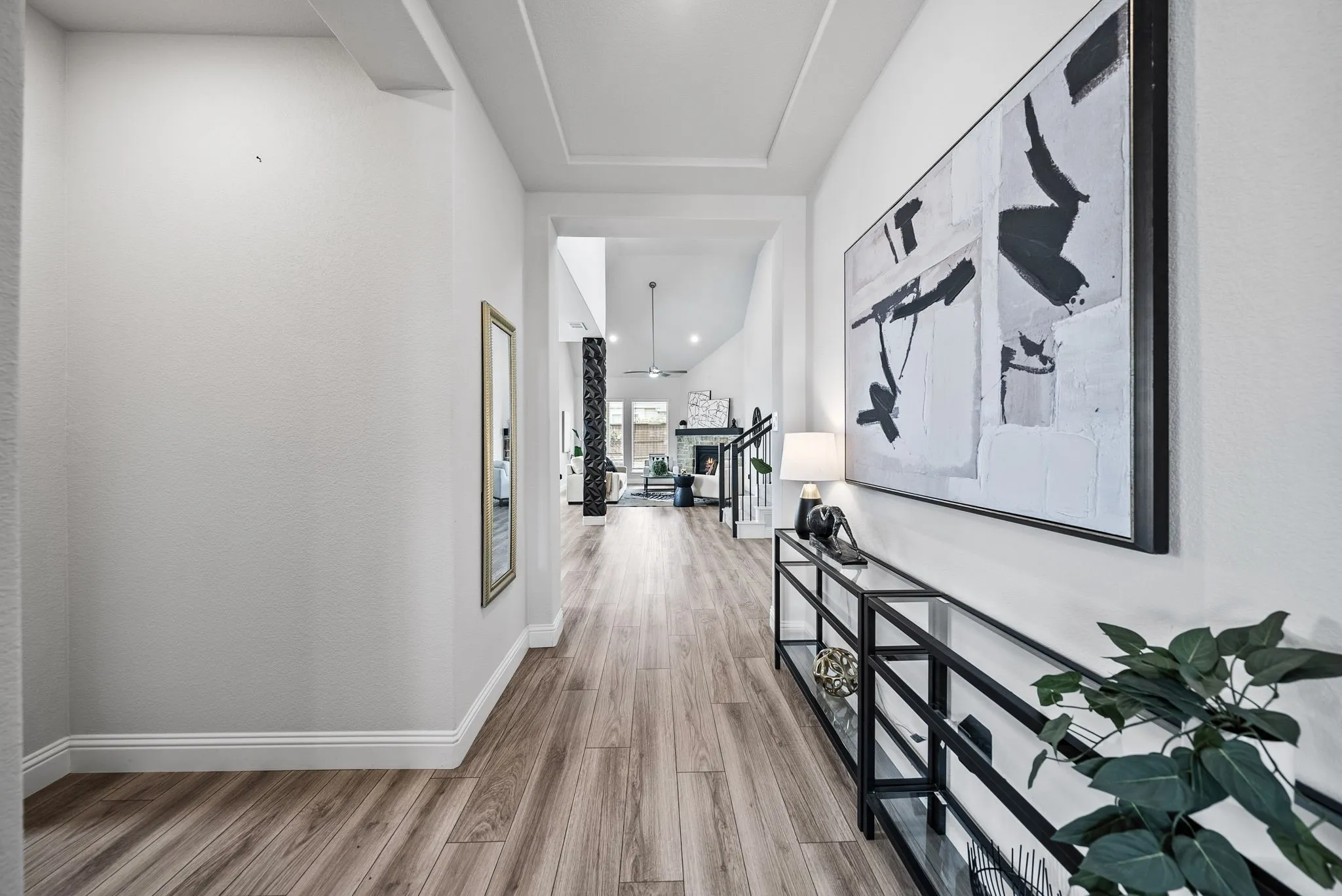 Wood-finish flooring throughout, tray ceiling detail, high ceilings, recessed lighting, and white baseboards