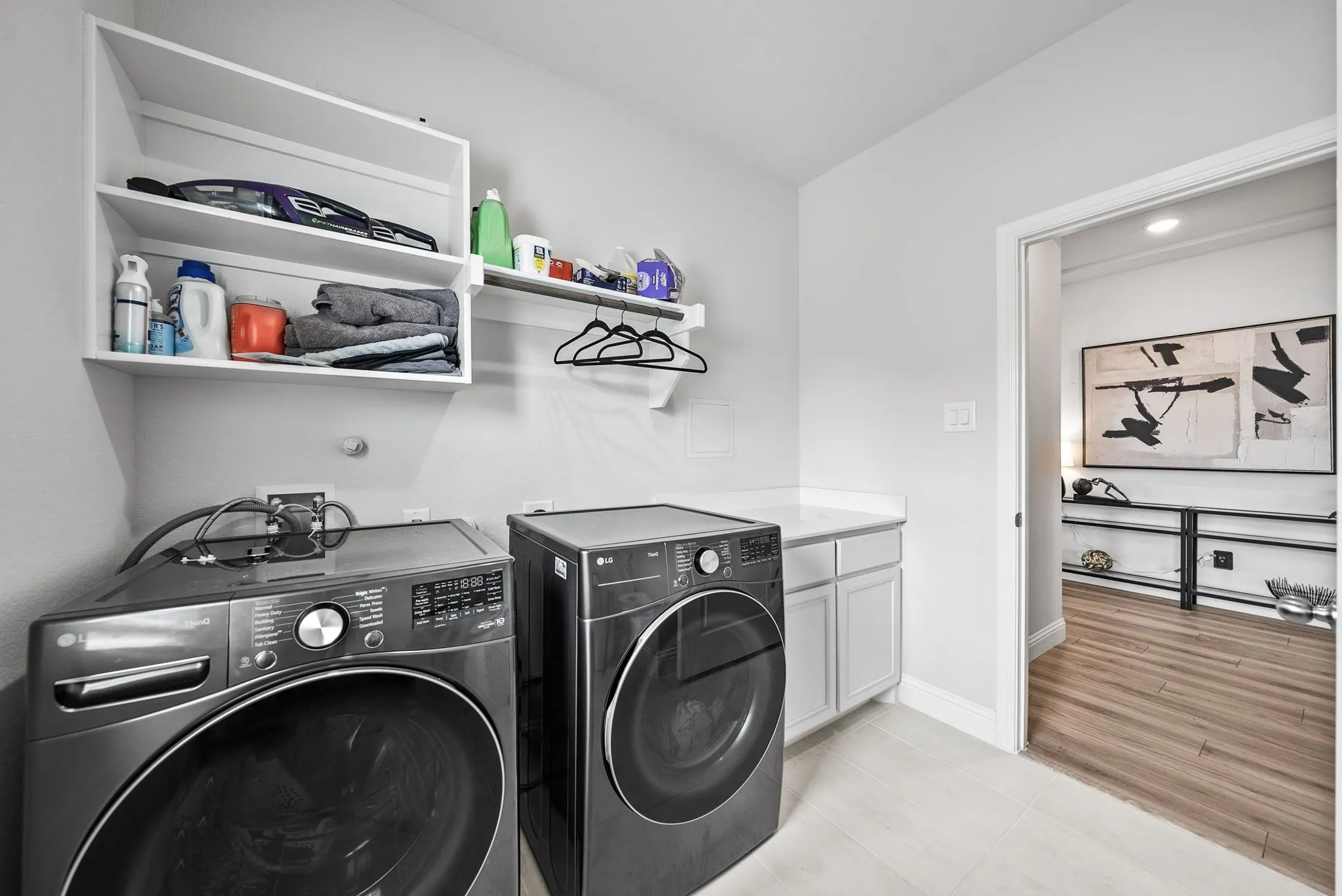Laundry area featuring white cabinetry, a light-colored countertop, and built-in shelving