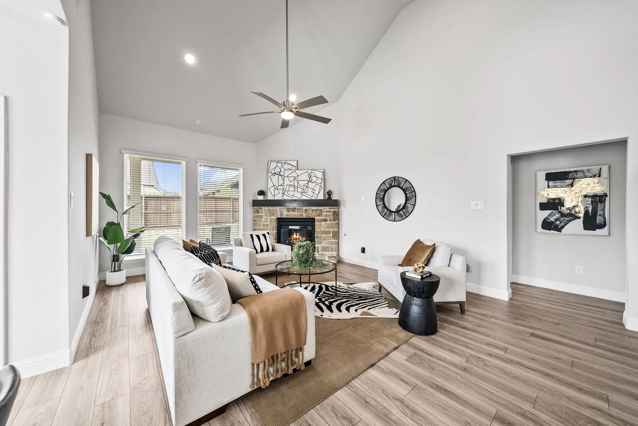 Vaulted ceilings, wood-finish flooring, and a stone-clad fireplace with a dark wood mantelpiece