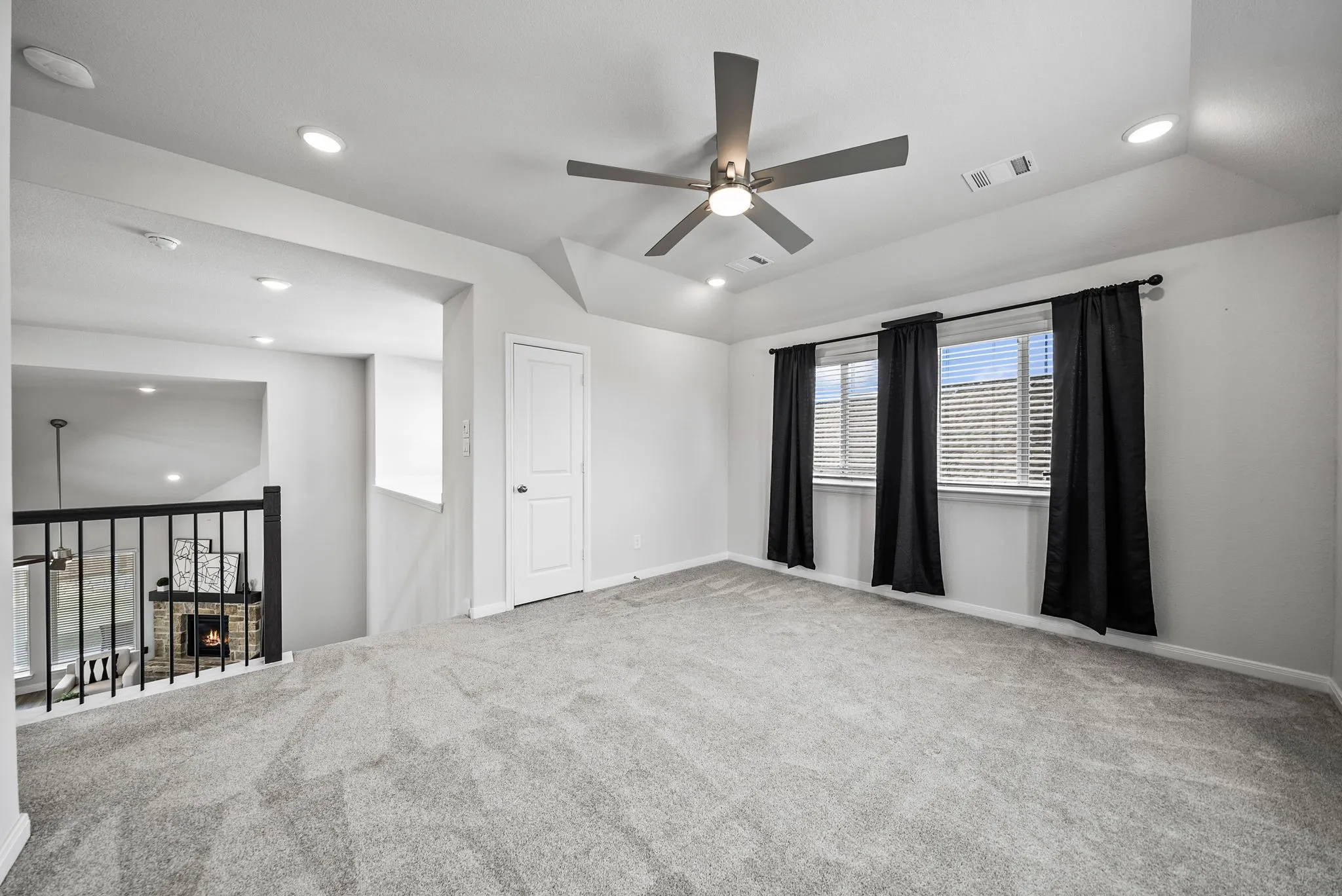 Lofted living space featuring soft gray carpeting, a contemporary ceiling fan, recessed lighting, and a white interior door