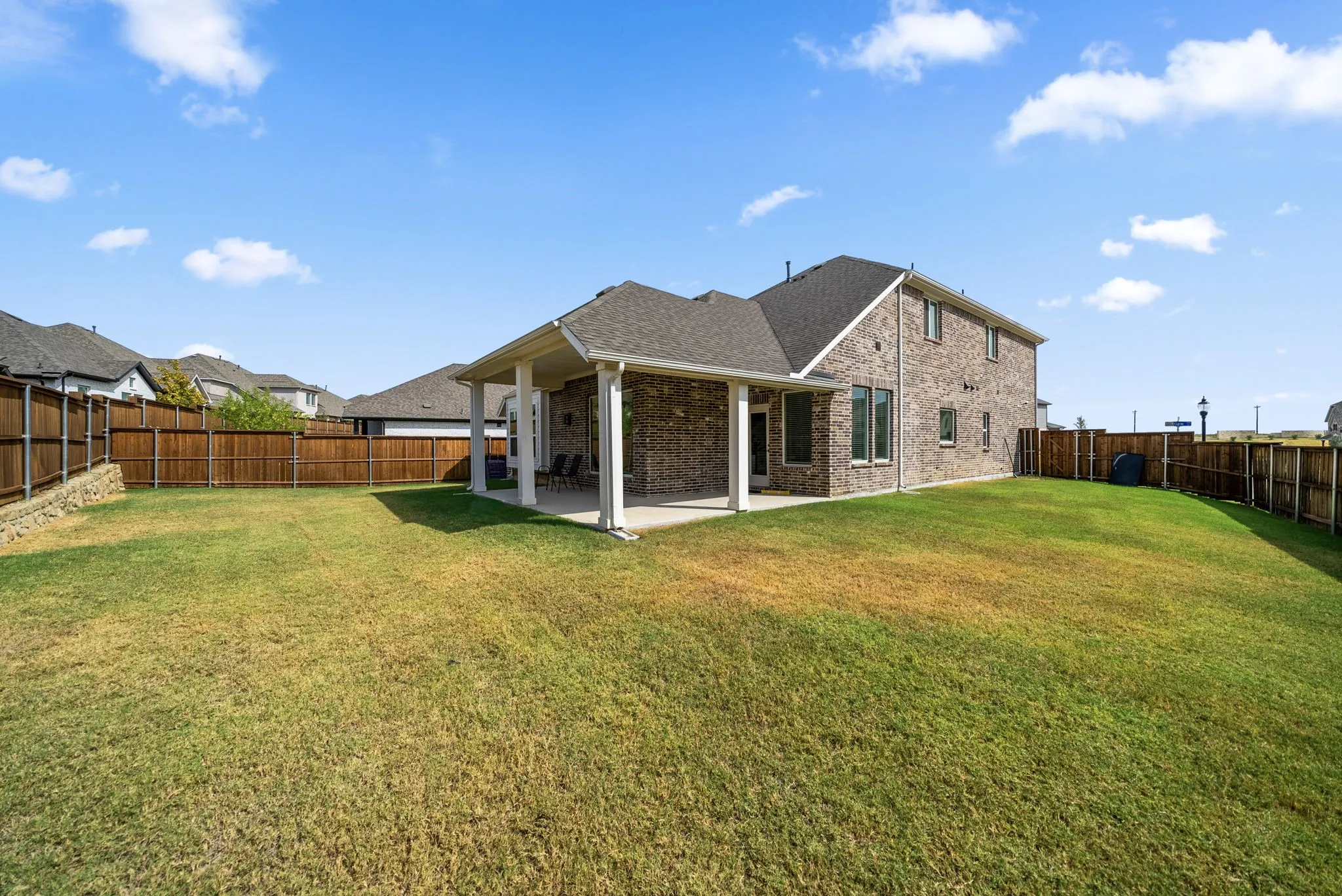 Spacious backyard featuring a covered patio, extensive lawn, and a full privacy fence