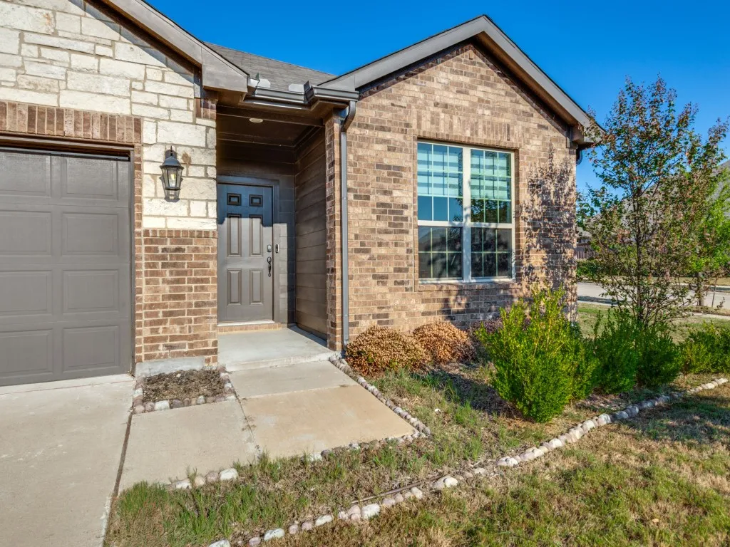 Charming brick residence featuring a covered entry portico, dual-pane windows with black frames, and an attached single-car garage
