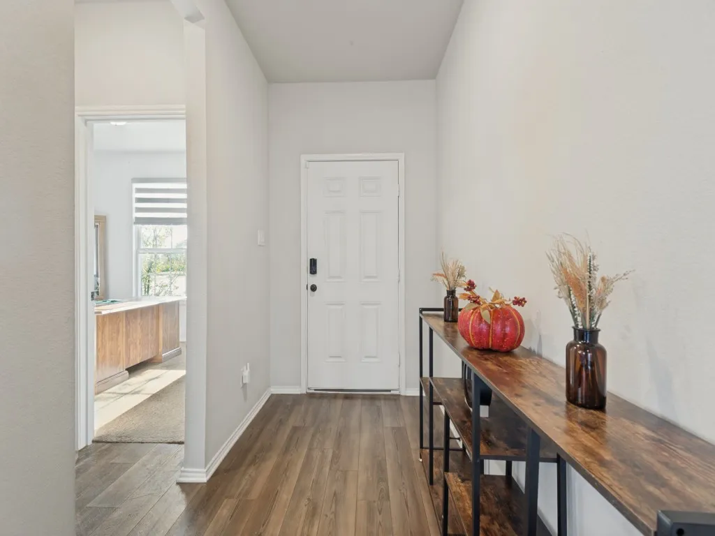Wood-finish flooring throughout, white interior door, and light-toned walls