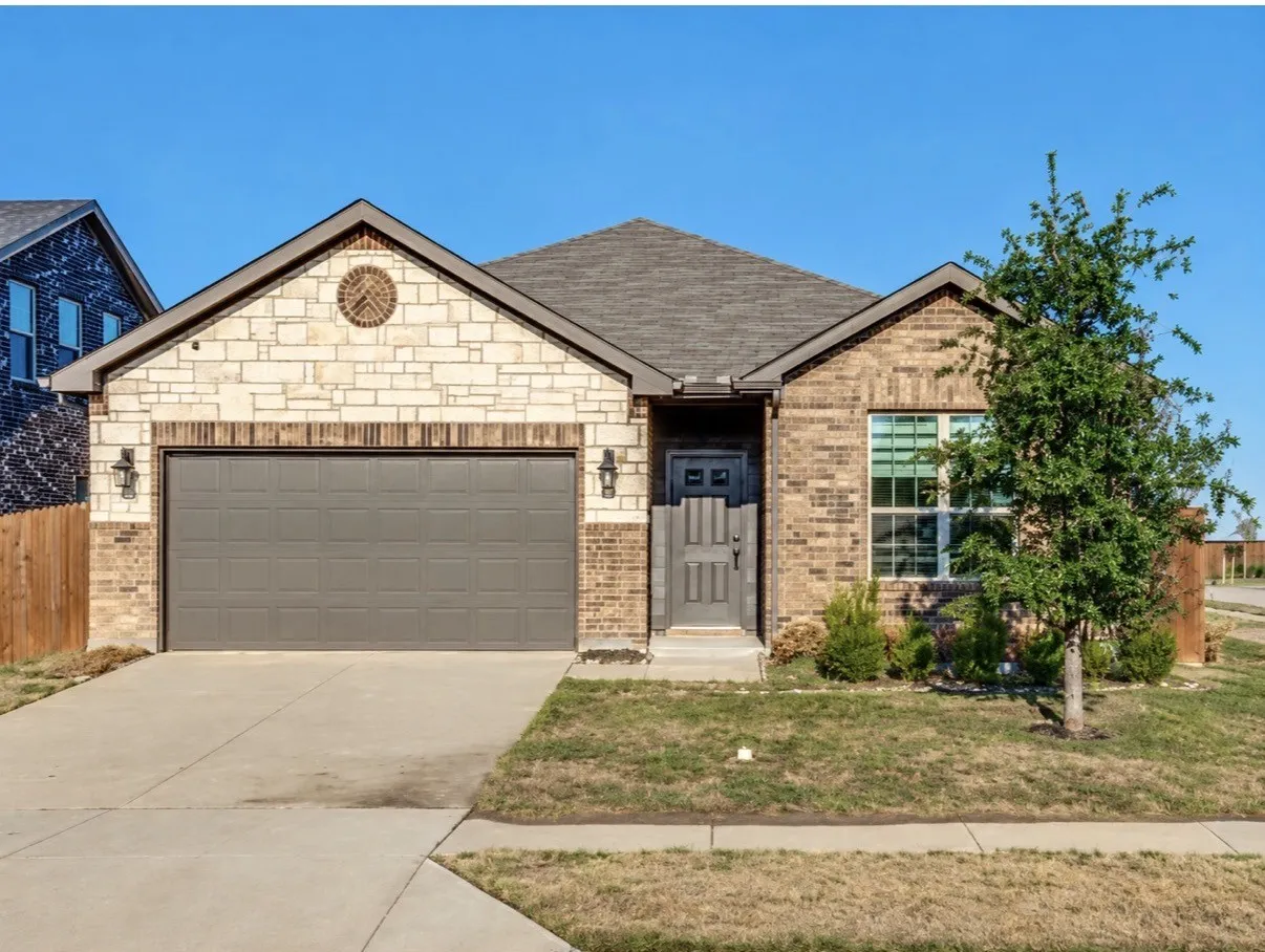 Charming single-story brick residence featuring a two-car garage with paneled doors, arched entry with sidelights, and large front-facing window