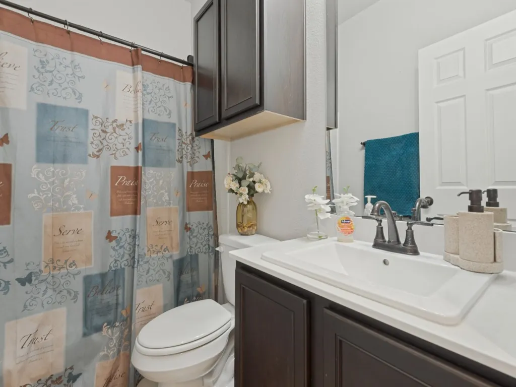 Recessed sink with dark wood-finish vanity, wall-mounted mirror, and cabinet storage