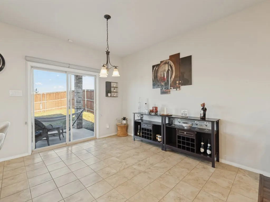 Porcelain tile flooring, sliding glass patio door, outdoor patio, backyard with privacy fencing, and a chandelier-style ceiling fixture