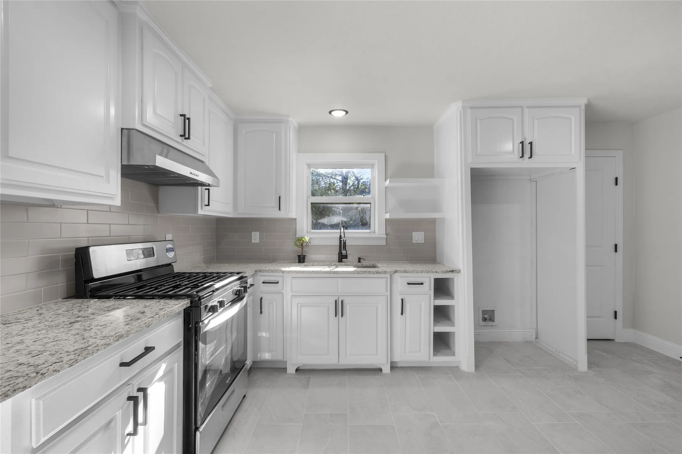 Kitchen featuring white cabinetry, light-colored countertops, stainless steel range with hood, a tile backsplash, and light-toned floor tiling