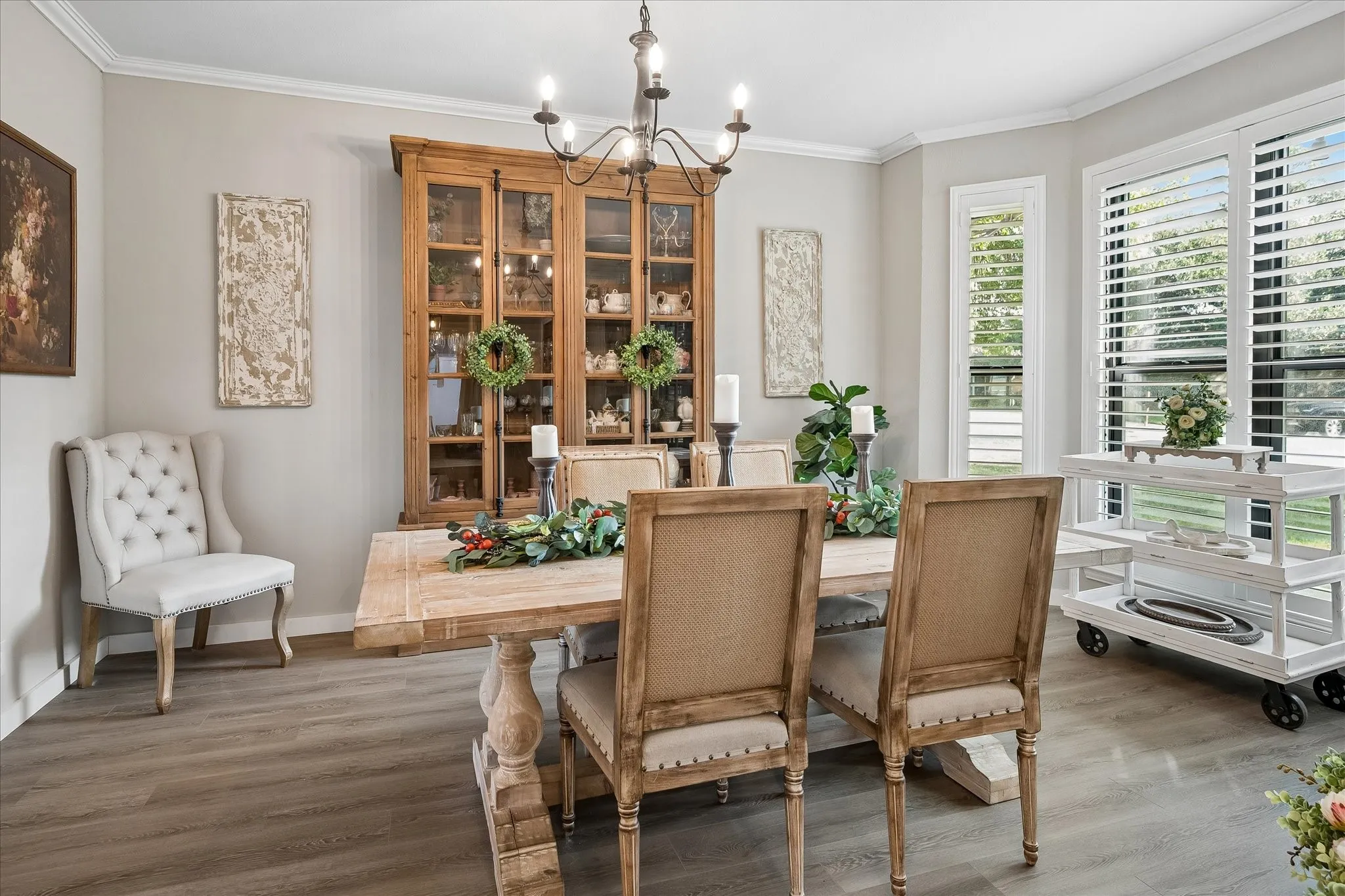 Wood-finish flooring, multi-pane windows with adjustable plantation shutters, crown molding, and a wrought-iron style chandelier