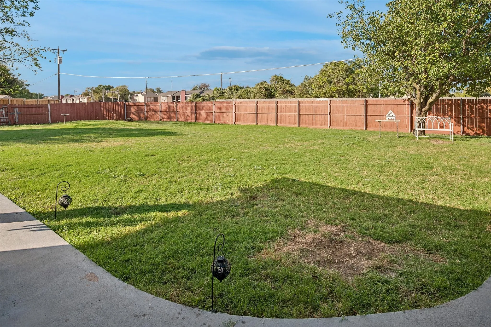 Expansive backyard featuring a concrete patio, a full-perimeter wood privacy fence, and mature trees