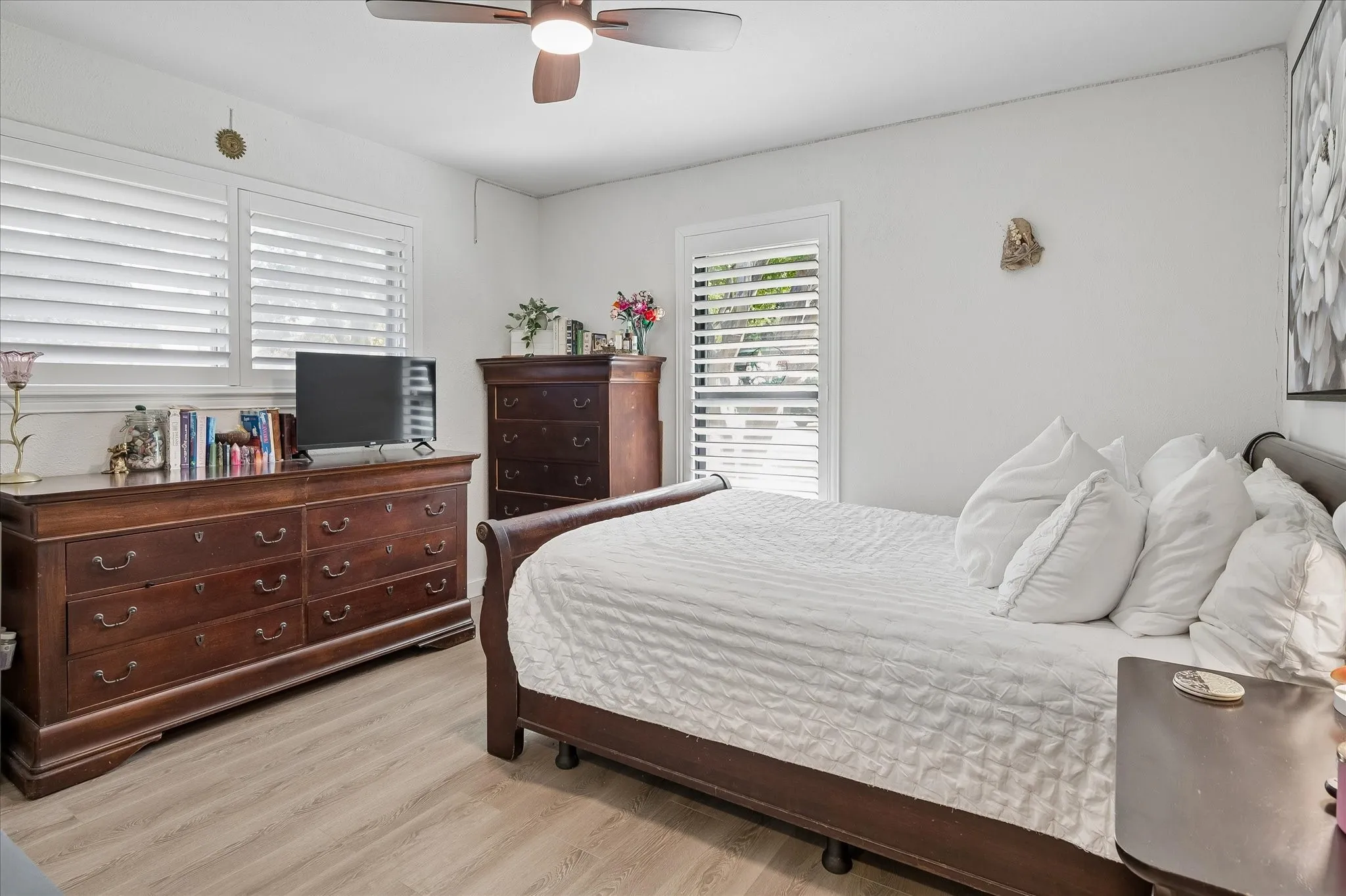 Wood-finish flooring, multi-pane windows with integrated white plantation shutters, and a ceiling-mounted light fixture with fan