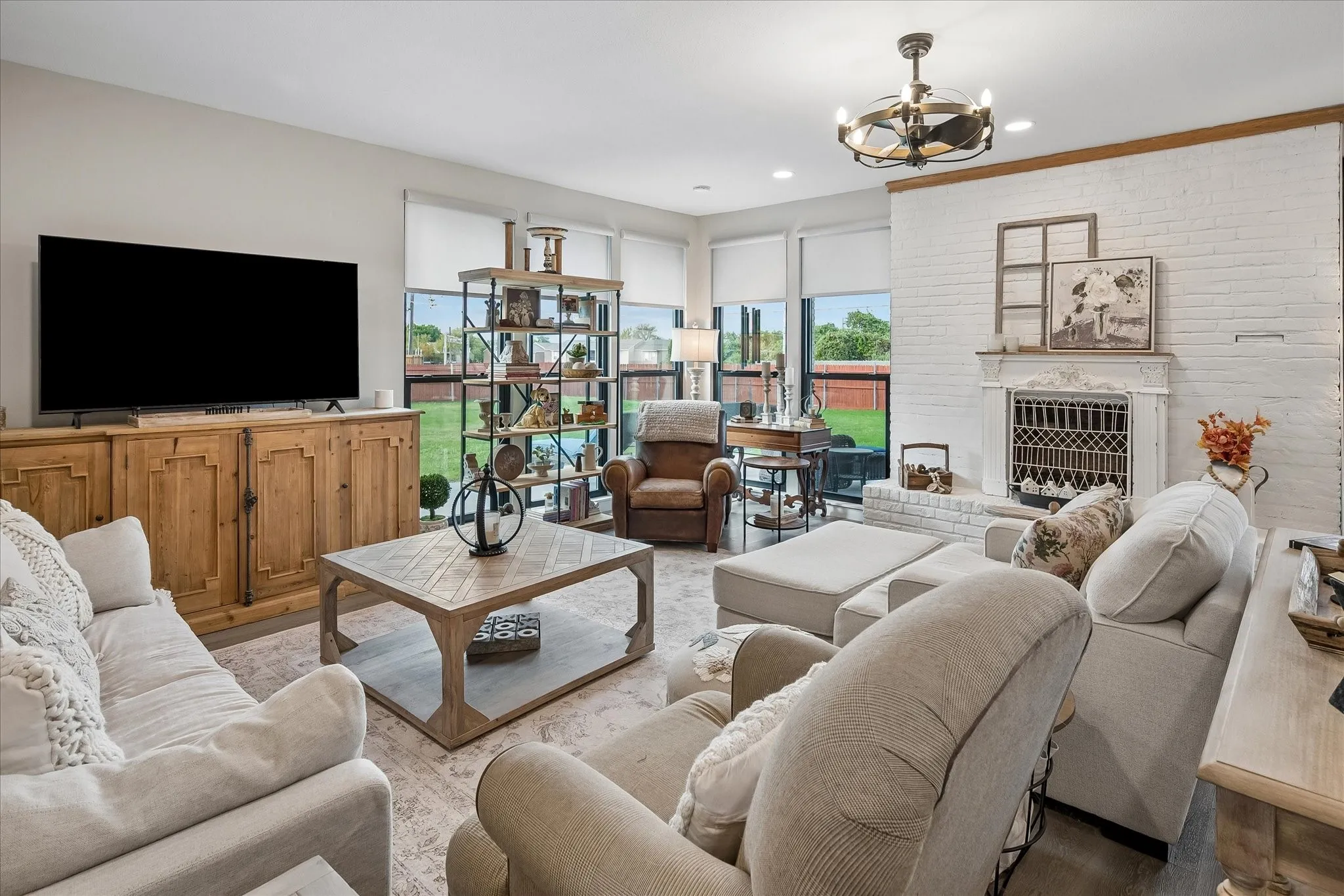 Living area featuring a floor-to-ceiling painted brick fireplace, built-in wooden media cabinetry, recessed lighting, and expansive windows