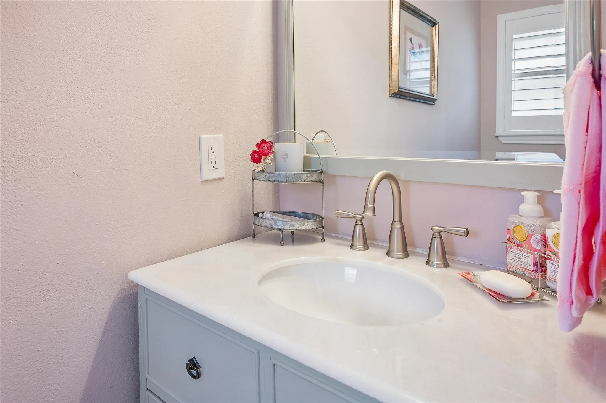 Bathroom vanity featuring a light-toned countertop with an integrated oval sink, brushed metal widespread faucet, neutral-toned cabinetry, and a large wall-mounted mirror