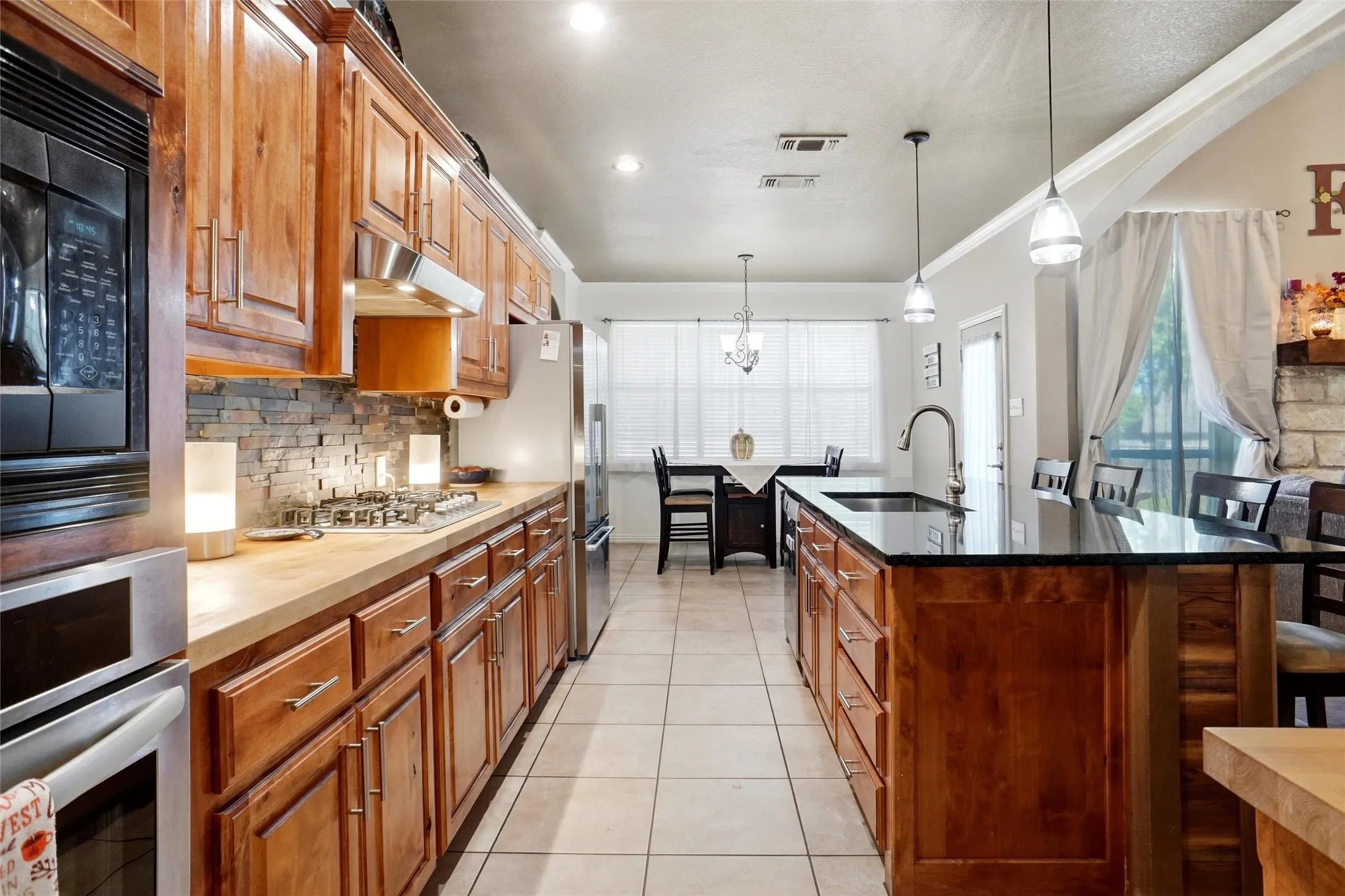 Kitchen with breakfast bar and dining area. Note butcherblock tops, in addition to lovely black granite! Bosch dishwasher.