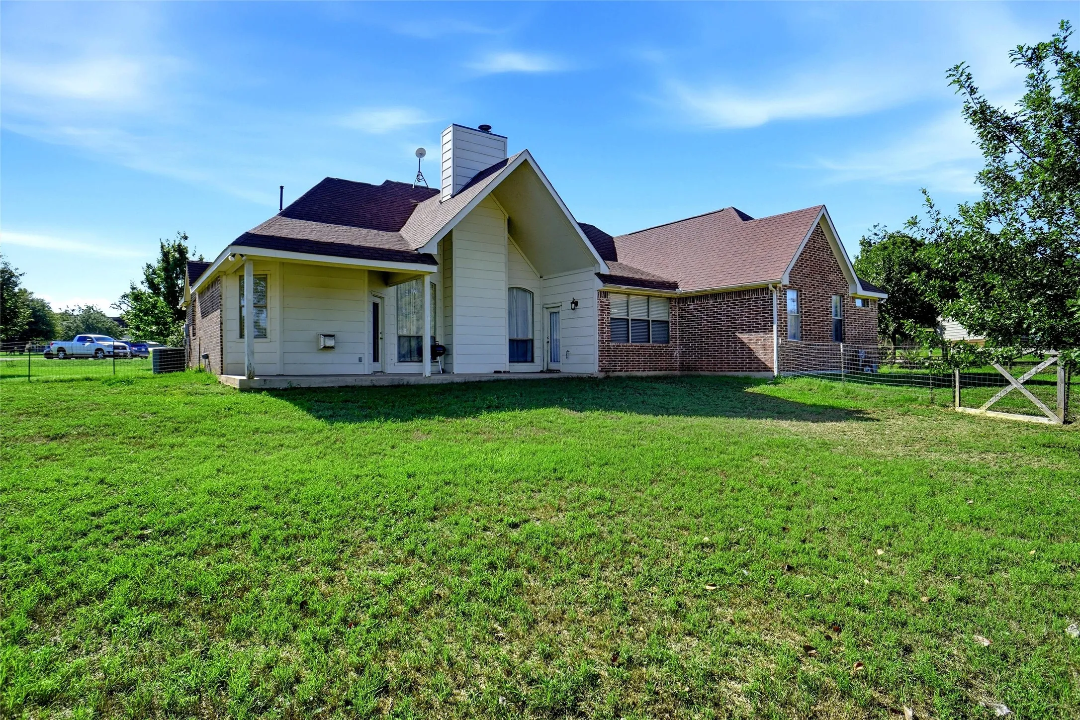 Rear of home with unique architectural features; fenced dog run area and patio.