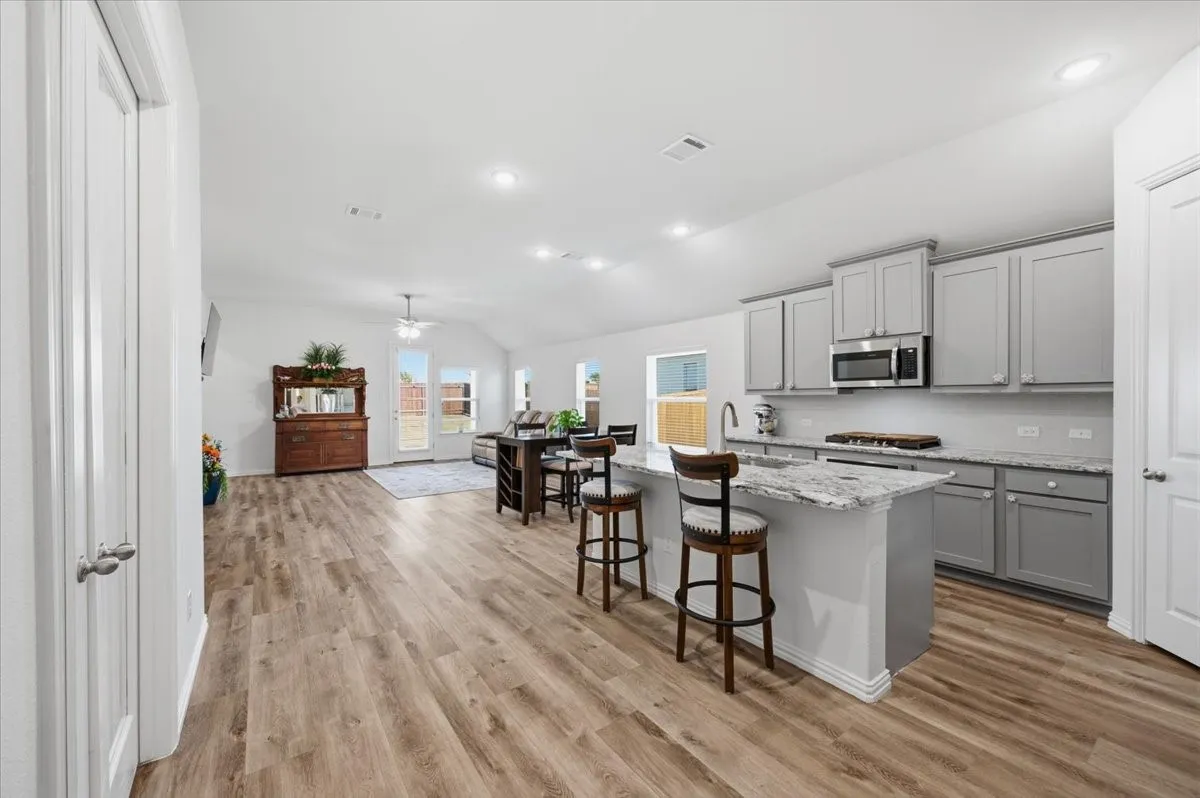 Open-concept layout with wood-finish flooring, recessed lighting, and vaulted ceilings