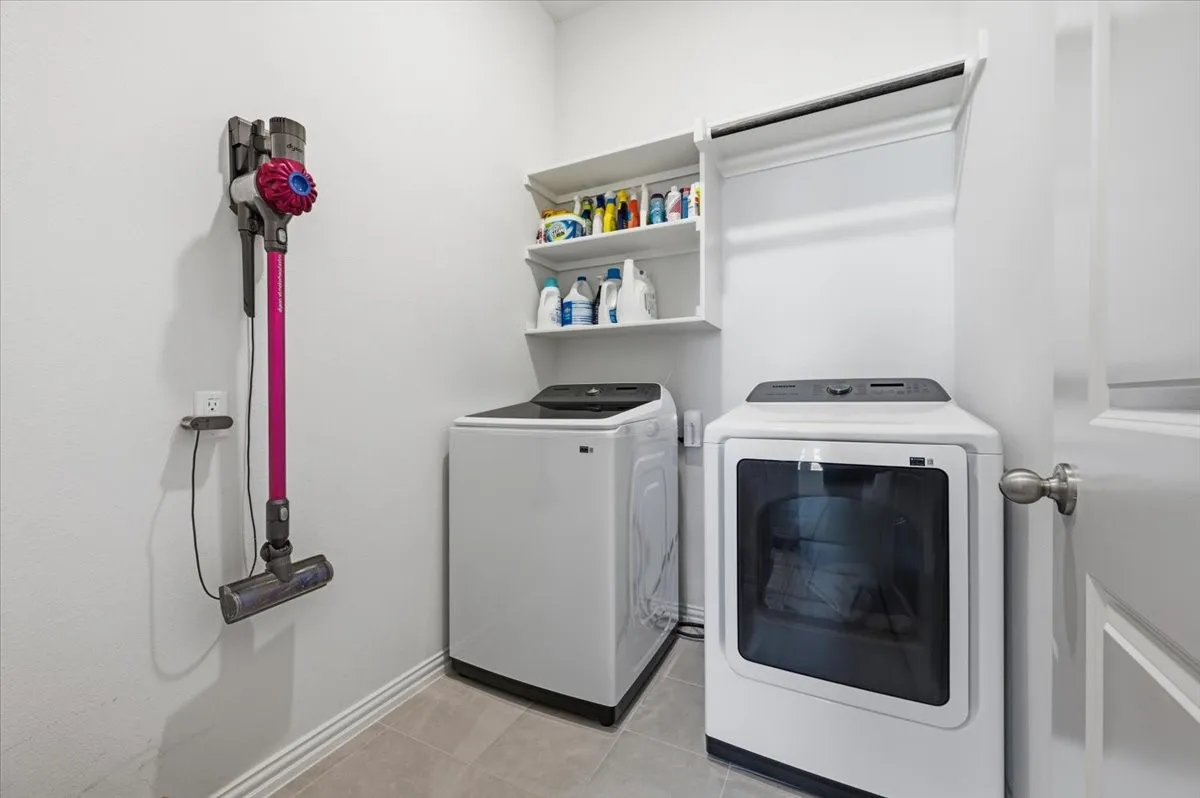 Laundry area featuring white built-in shelving, a built-in hanging rod, and tile flooring