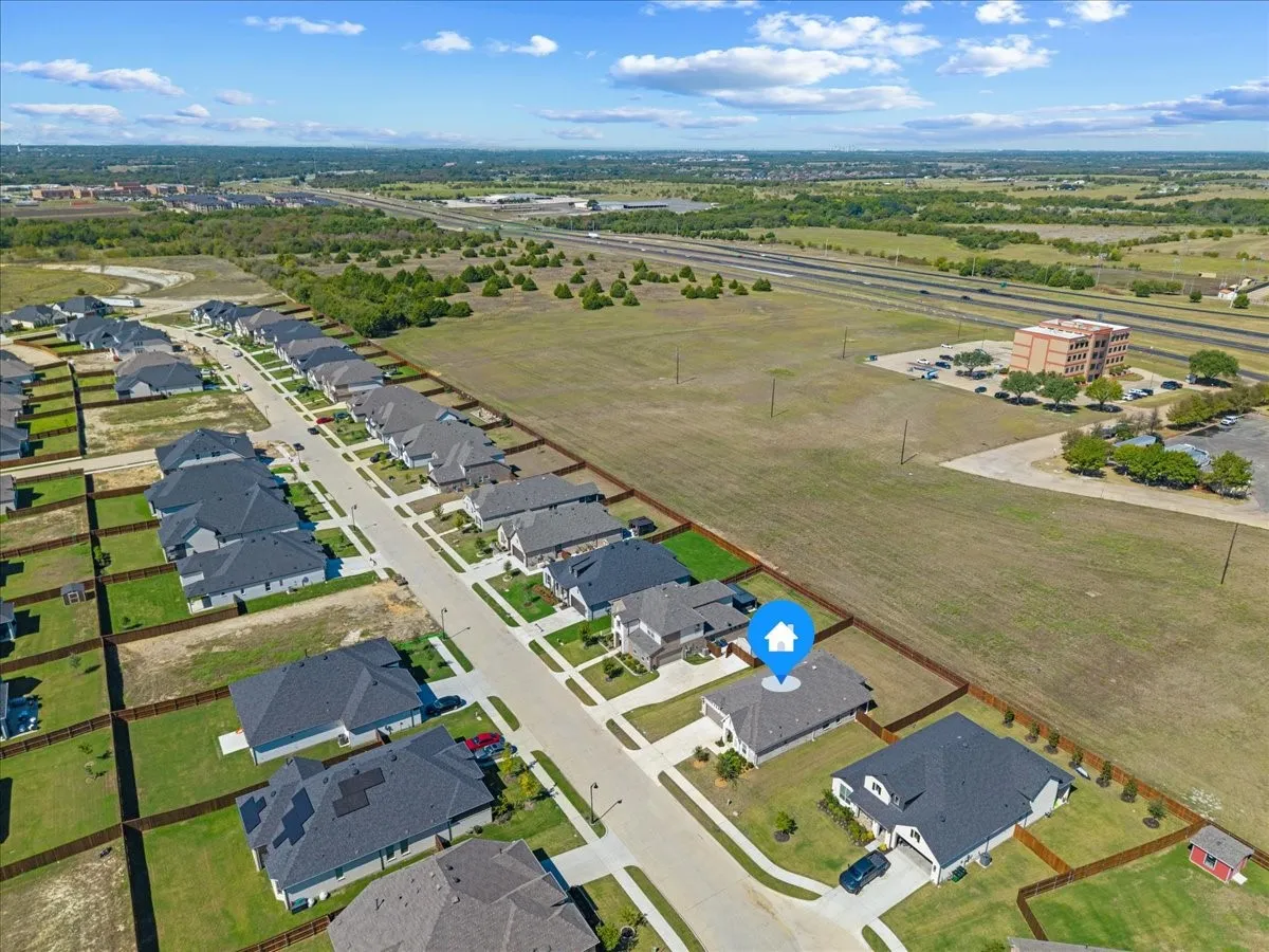 Newly constructed residential development featuring a structured street layout, uniform property fencing, and a defined lot for the featured property