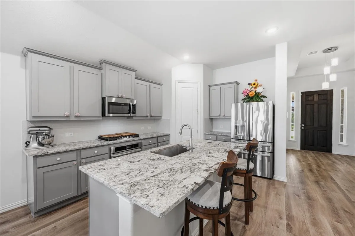 Kitchen featuring light gray cabinetry, stainless steel appliances, granite countertops, and wood-finish flooring