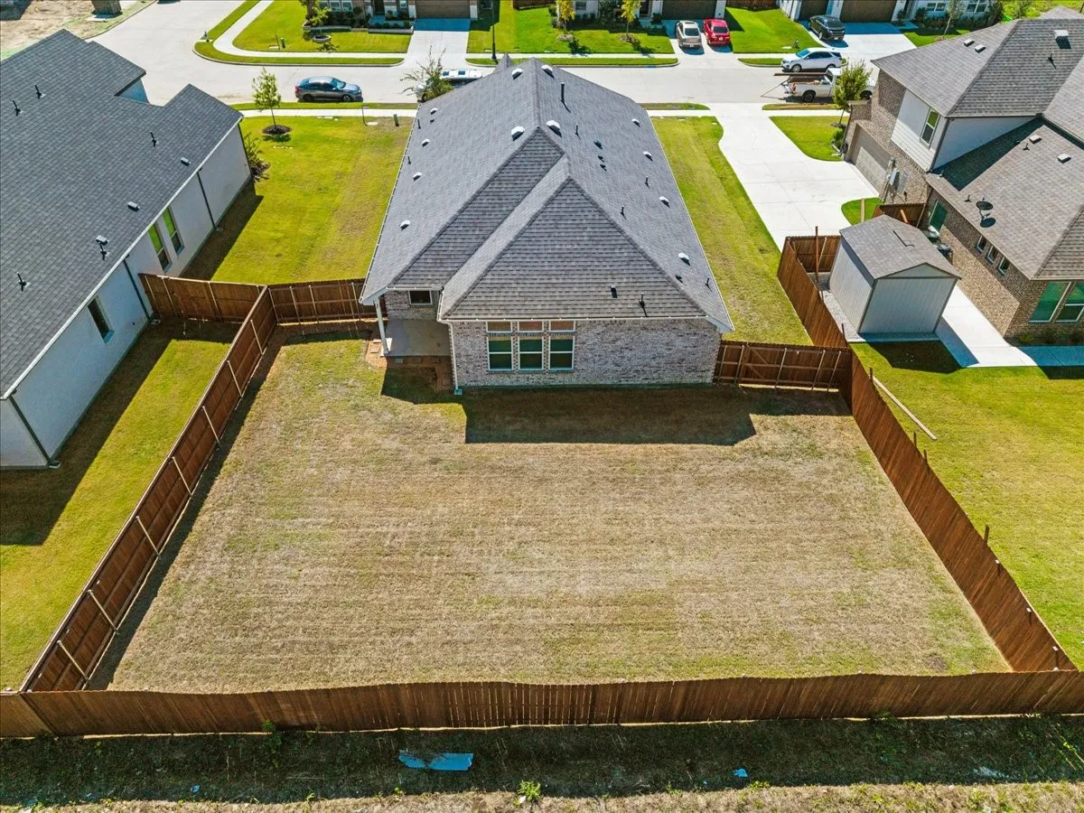 Enclosed backyard featuring a wood fence, a brick and siding exterior, and a shingle roof