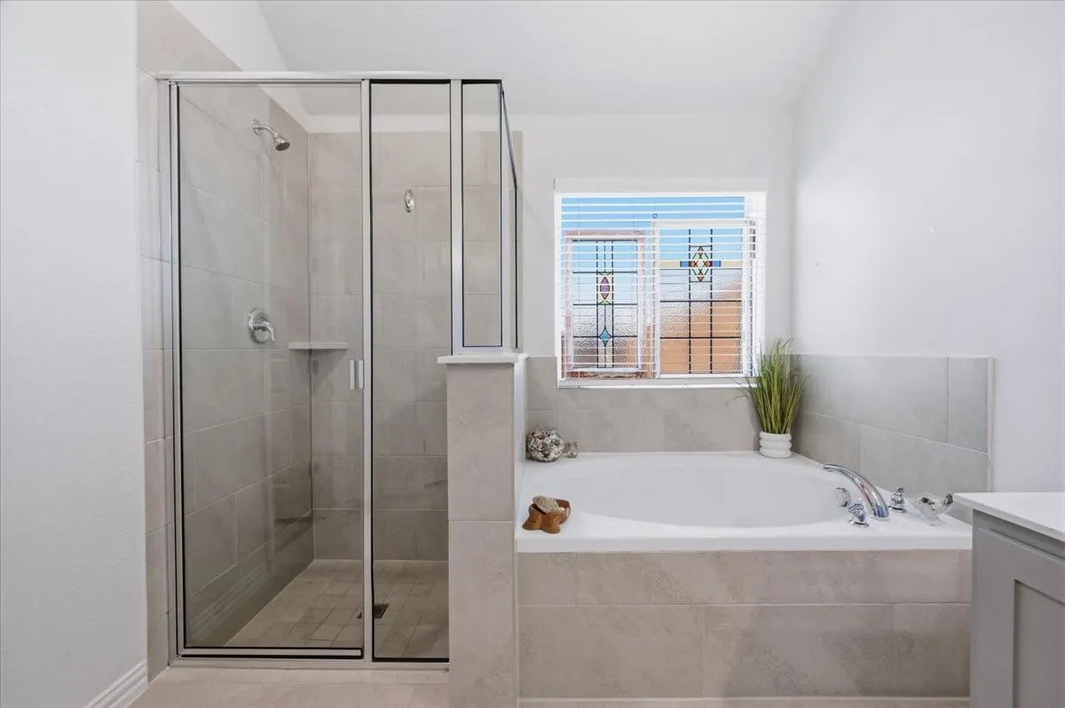 Walk-in shower with clear glass enclosure and light-toned tile surround