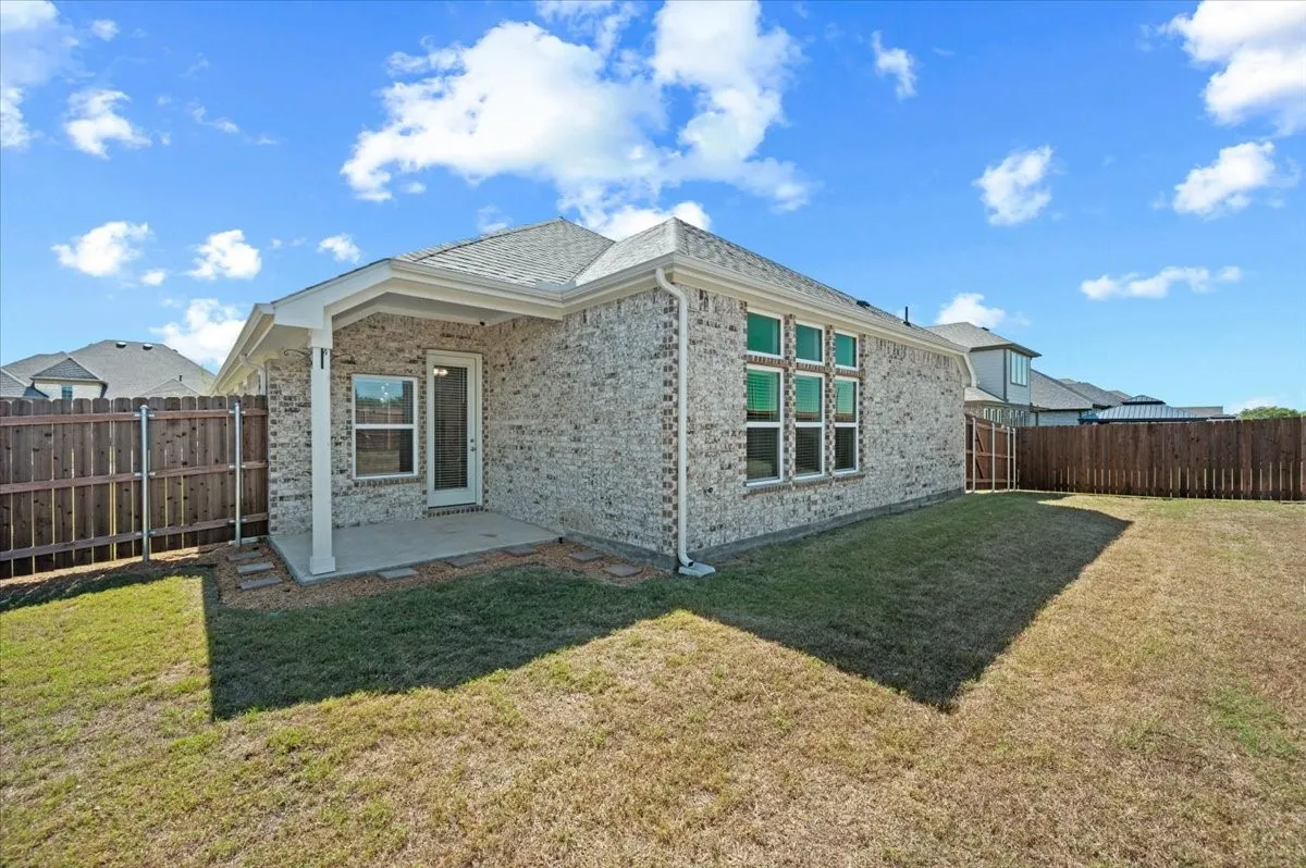 Rear exterior featuring a covered concrete patio, brick facade, and multiple pane windows