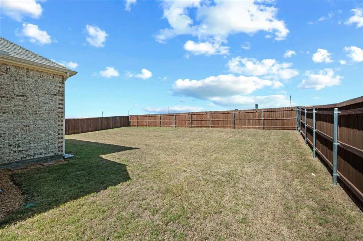 Expansive backyard with a full perimeter wood privacy fence, featuring a partial chain-link fence section