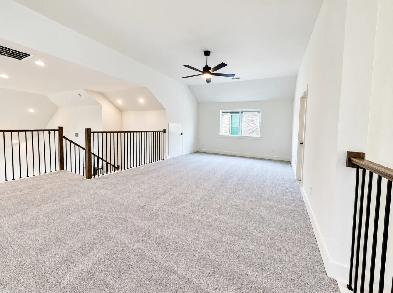 Spacious loft area featuring light-colored carpet, a ceiling fan, recessed lighting, and a window