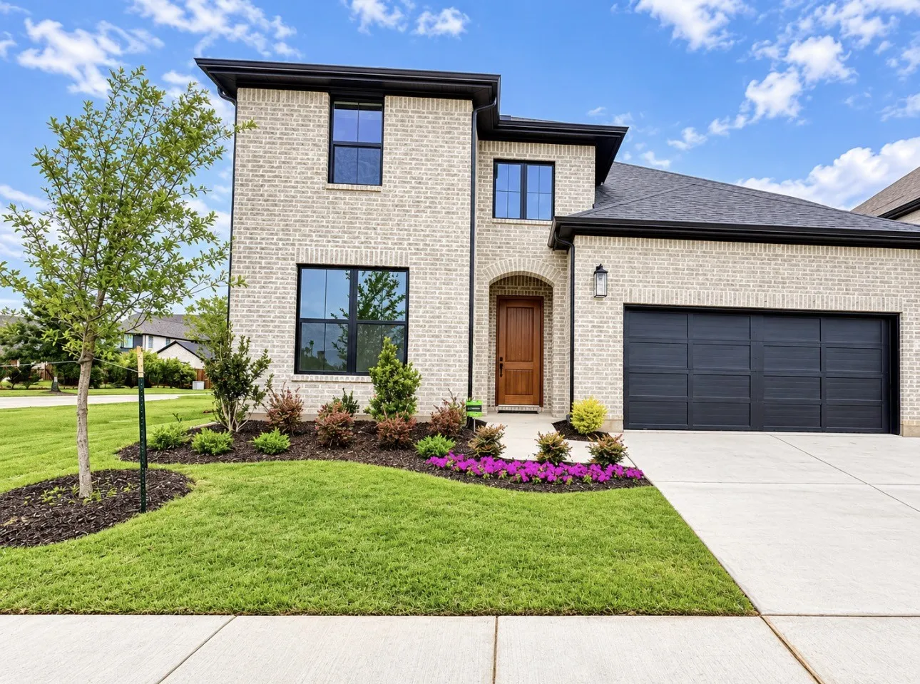 Light brick exterior with black window frames, an arched entryway, and a dark wood-finish front door